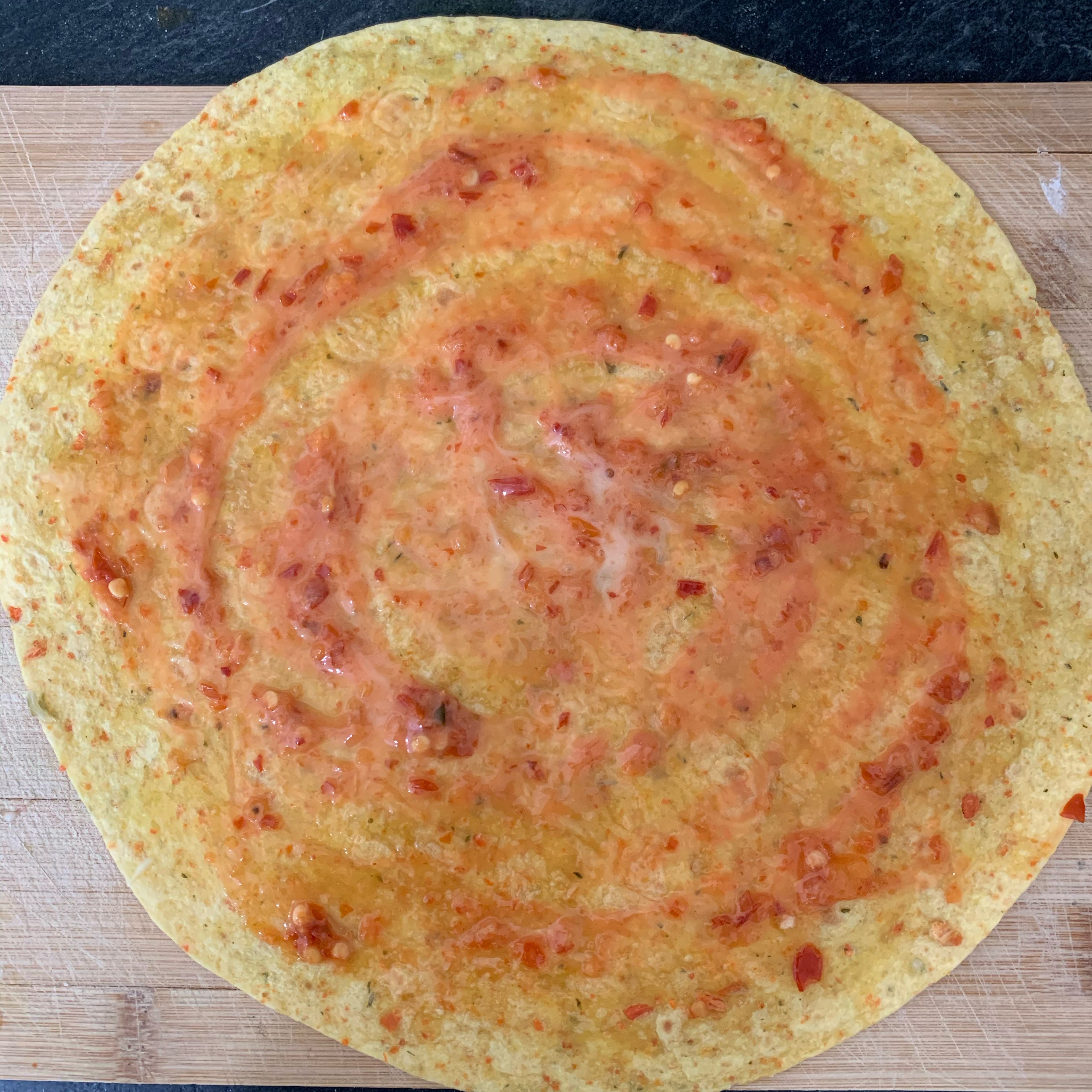 Add chilli sauce and coleslaw dressing on large-size tortilla and spread it evenly all over the base.