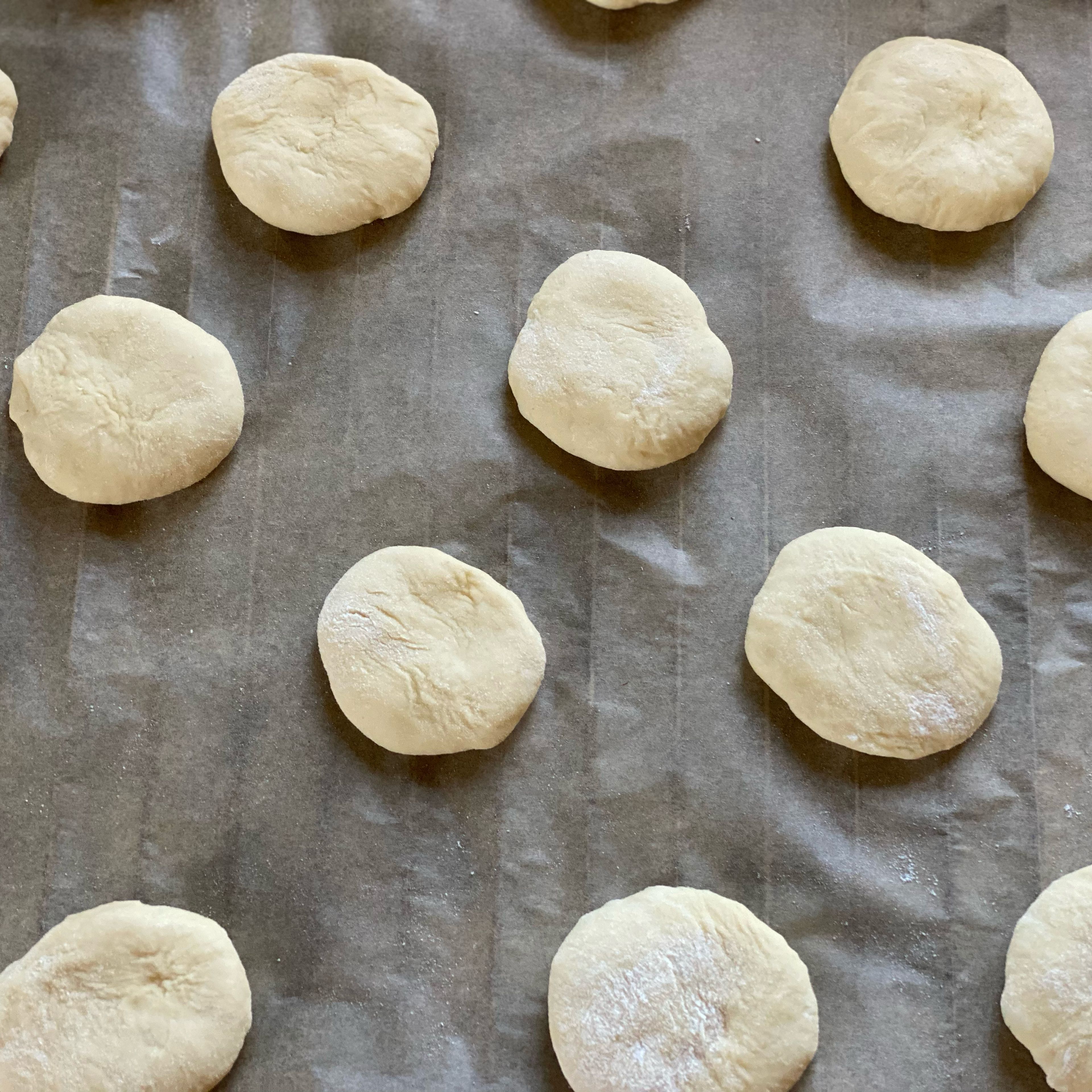 Den Teig auf 15 Stücke aufteilen, in Runde flachere Buns formen, Backblech mit Backpapier auslegen
