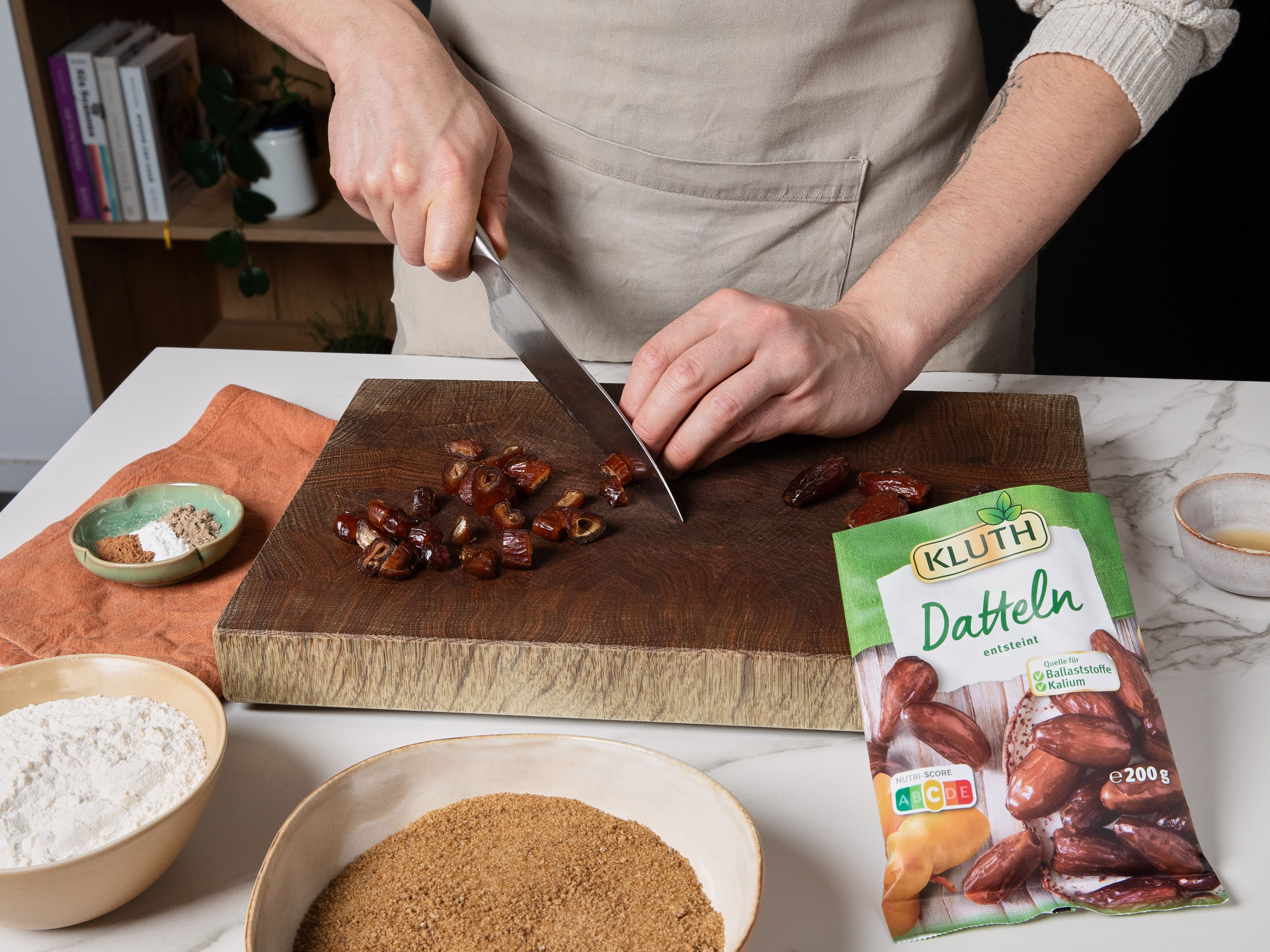 Den Ofen auf 180 °C (Ober-/Unterhitze) oder 160 °C (Umluft) vorheizen. 8 Muffinförmchen (ca. 5 cm hoch) einfetten oder alternativ eine 20 cm Backform einfetten und mit Backpapier auslegen, sodass es an den Rändern übersteht. Datteln hacken und in eine Schüssel geben, Natron darüberstreuen und mit kochendem Wasser übergießen. Ca. 15 Min. stehen lassen. Währenddessen die Toffee-Soße zubereiten.