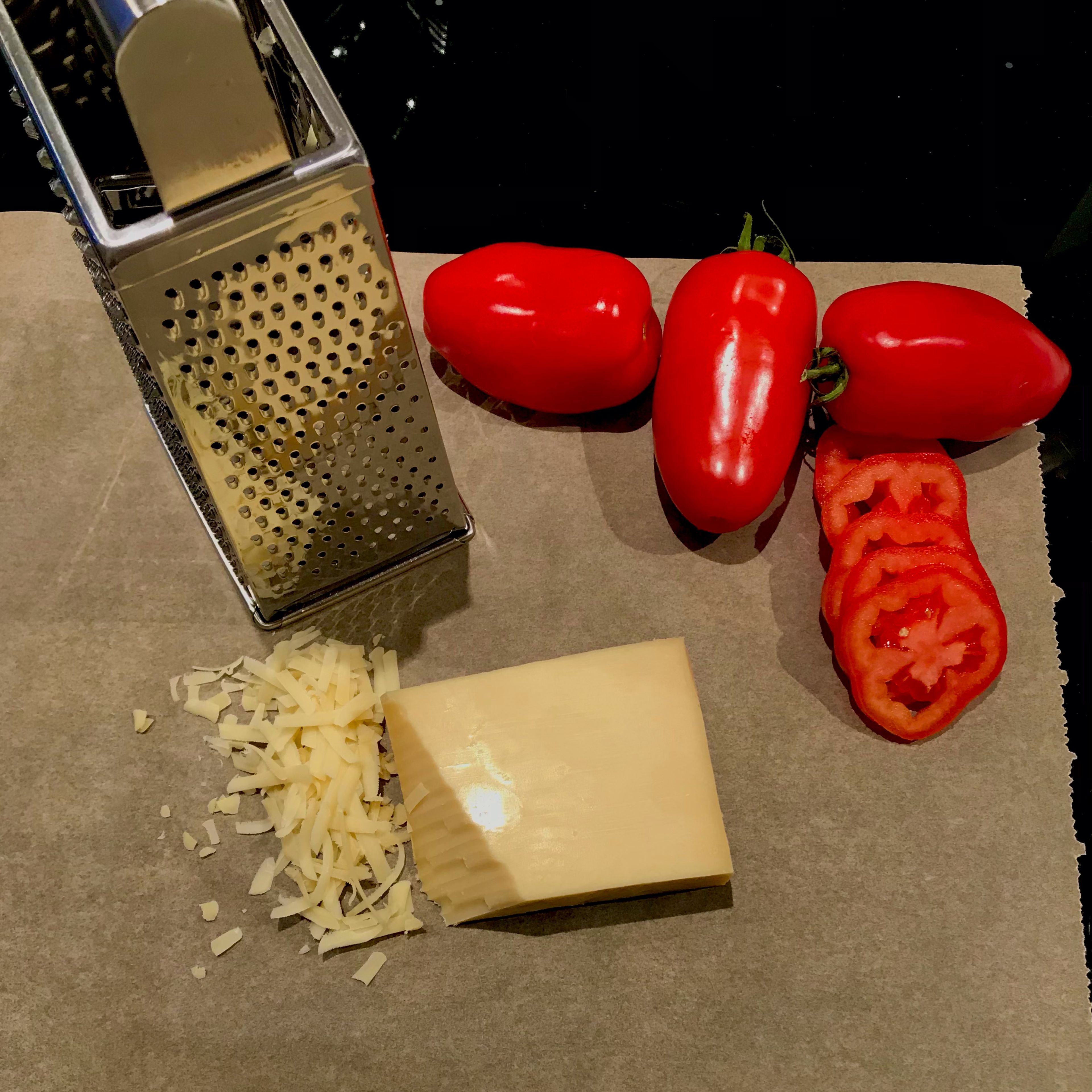 Den Käse reiben und die Tomaten in Scheiben schneiden.