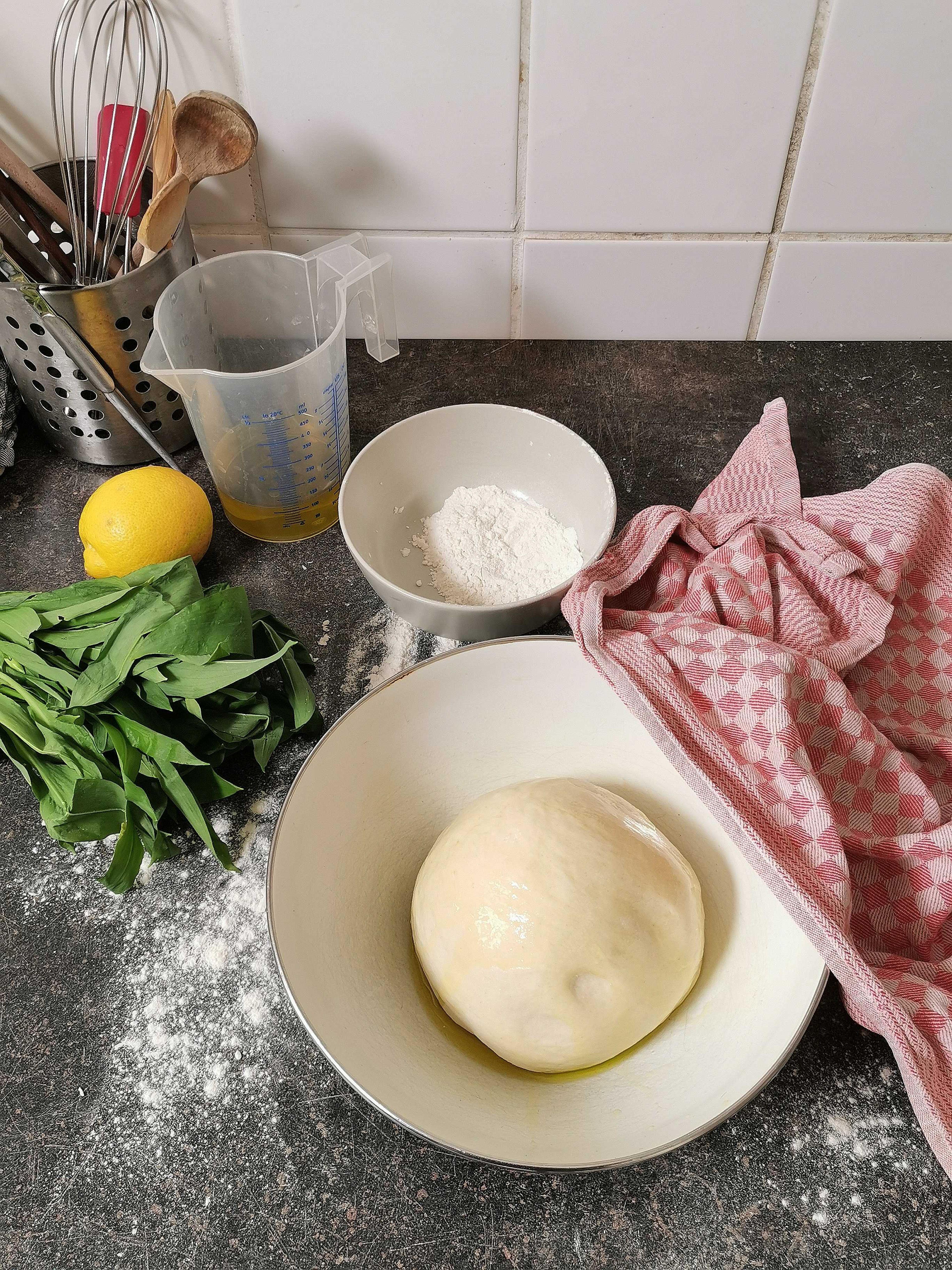 Transfer dough to a floured work surface and knead it with your hands until it's smooth and elastic. Grease a large bowl with olive oil, add the dough, cover with a damp kitchen towel, and let rise in a warm place for approx. 1 hr.