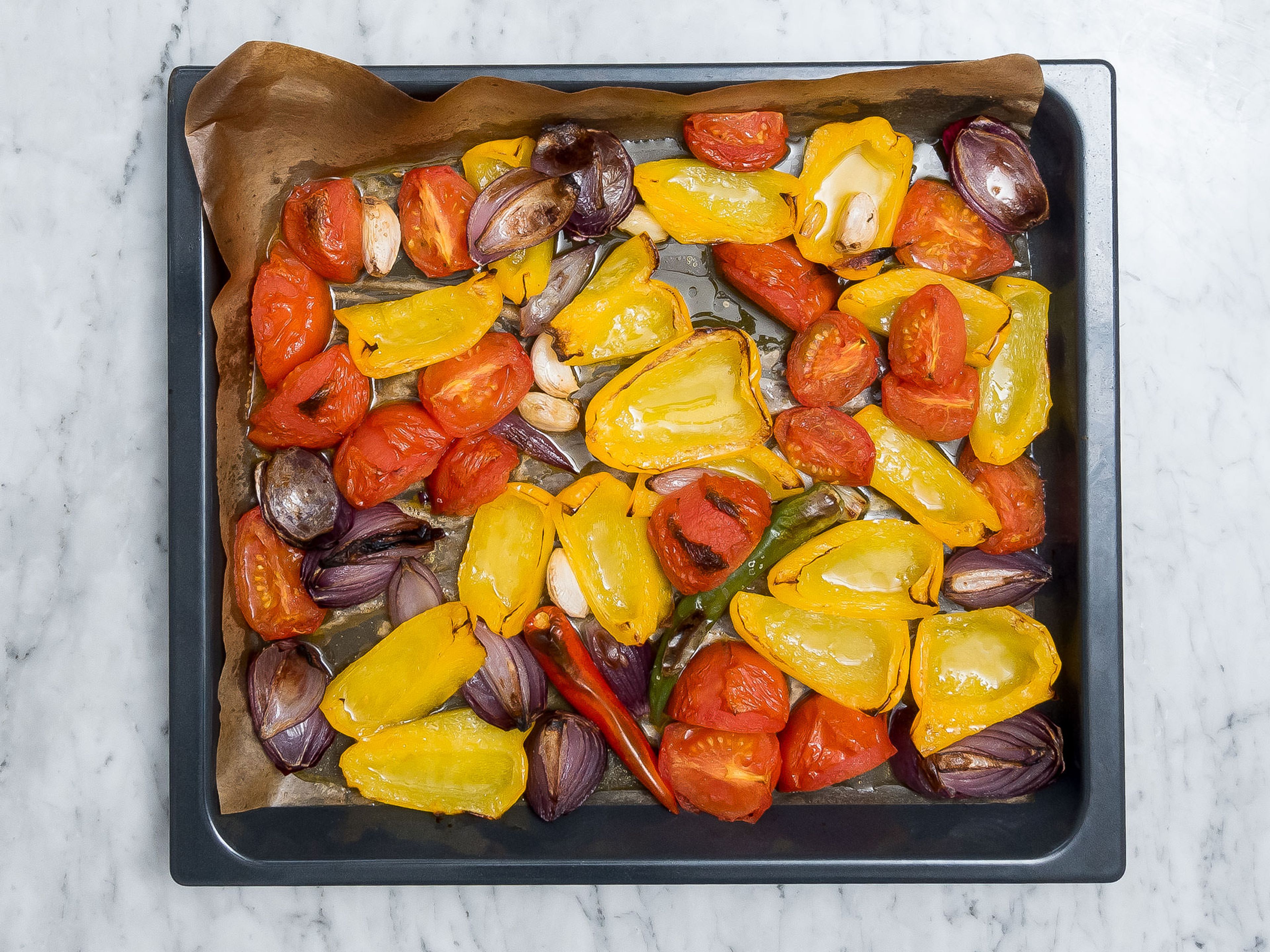 Transfer sliced vegetables together with the garlic and chili peppers to a parchment-lined baking sheet and bake in oven at 240°C/460°F, using the grill function, for approx. 15 min. Remove from oven and turn vegetables, make sure to turn the bell peppers skin-side up. Place back into the oven and bake for approx. 15 – 20 min. more, or until vegetables turn slightly brown. Remove from oven.