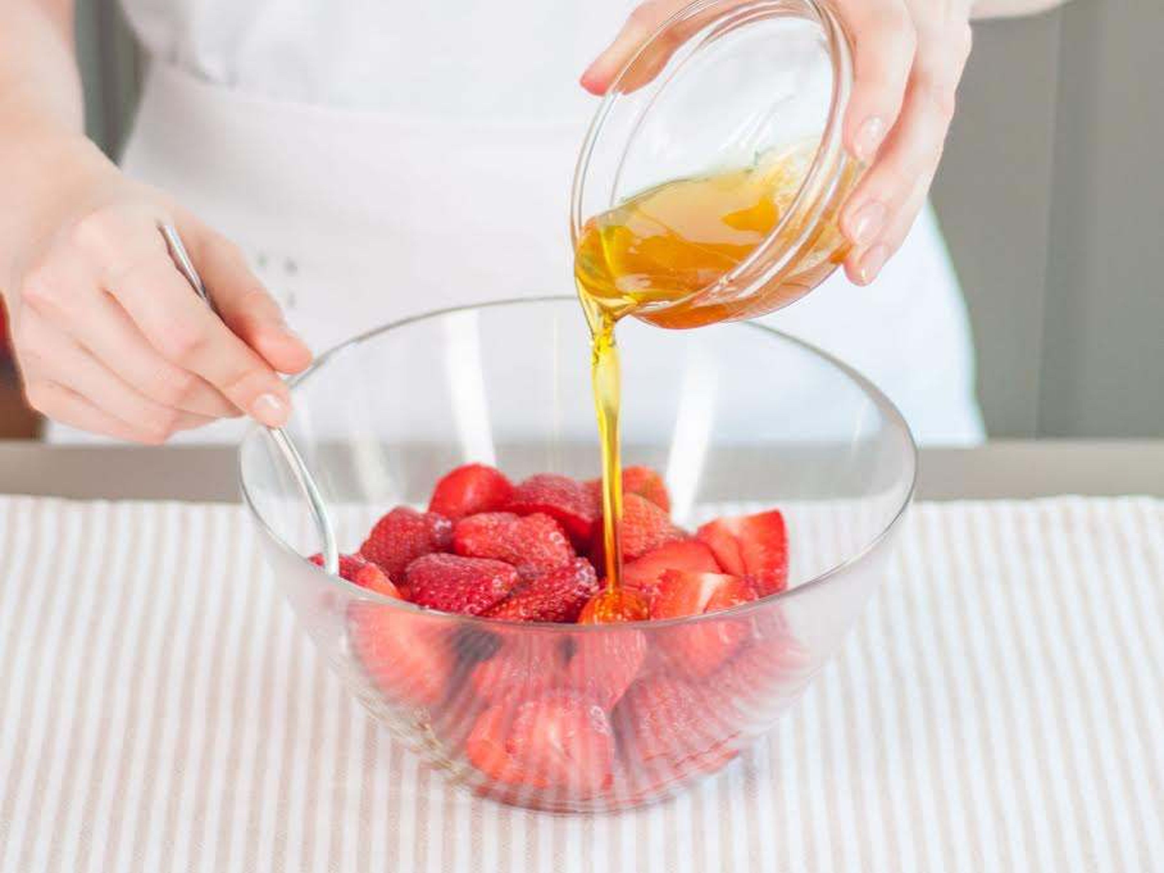 Honig, Olivenöl und einen Teil des Salzes miteinander verrühren. Die Mischung zu den halbierten Erdbeeren geben und gut vermengen.