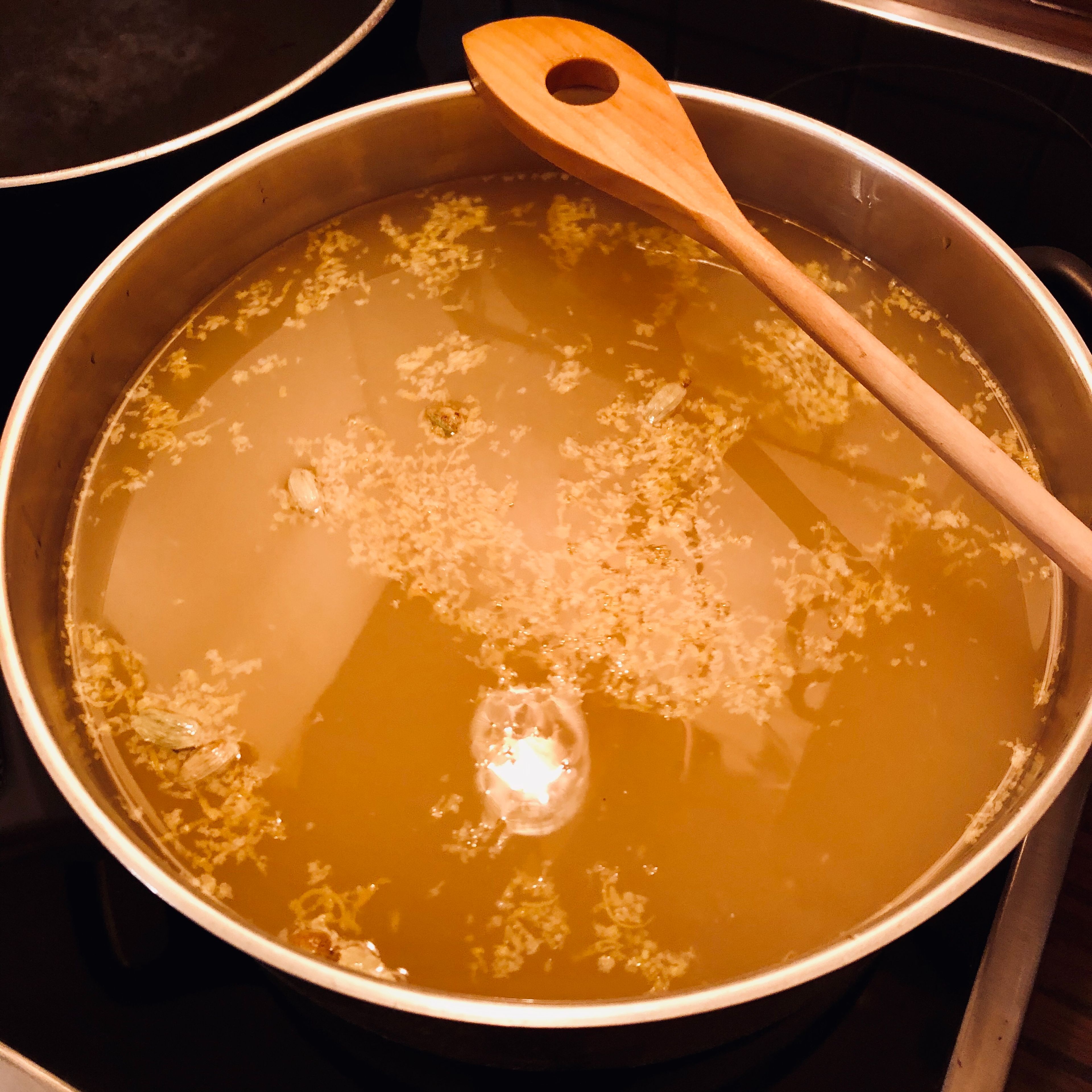 Apfelsaft und Limejuice in einem Topf langsam erhitzen. Zimtstangen, Zitronenschale und Kardamon nach 10 min in einem Teesieb dazugeben.