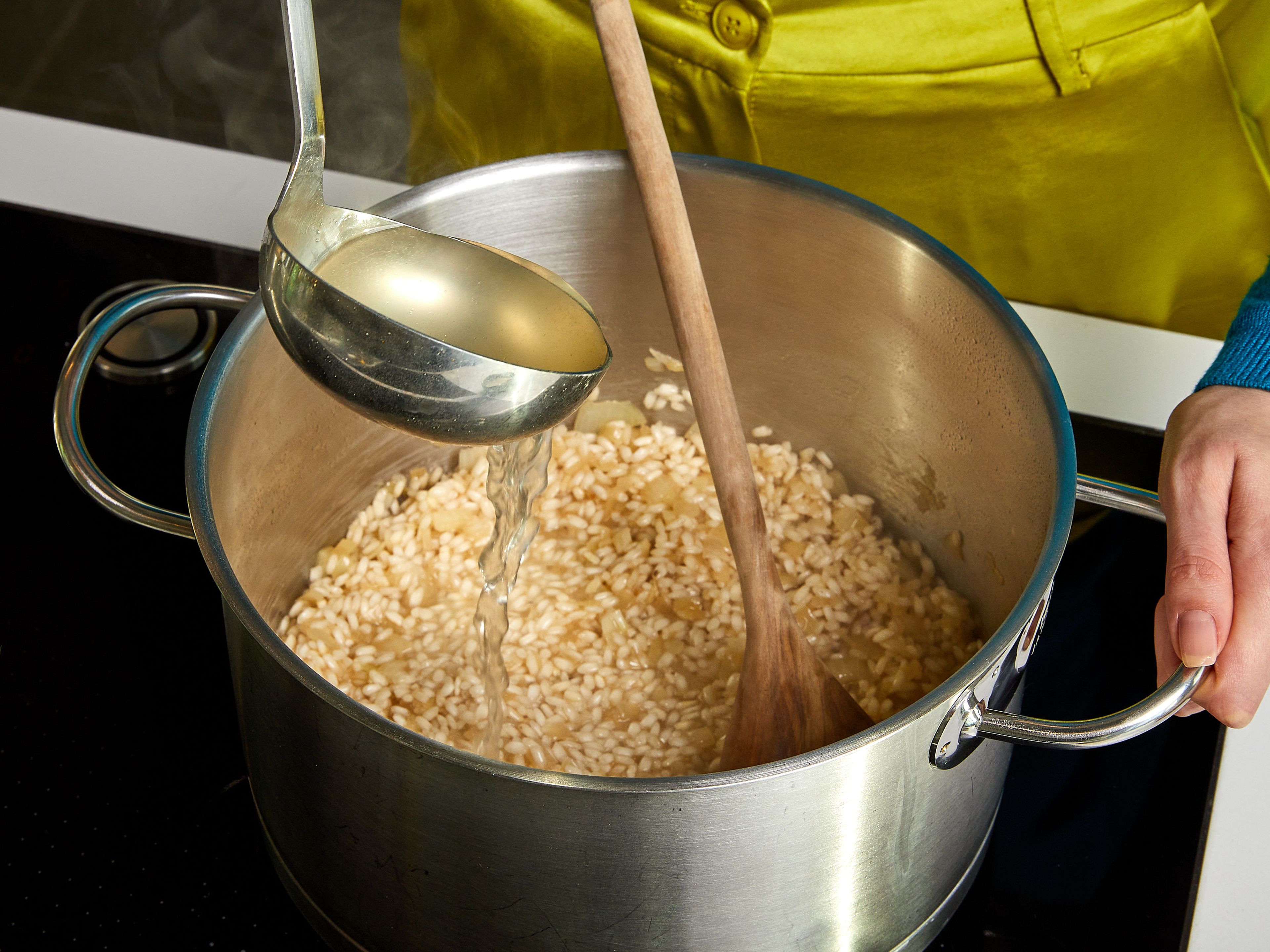 Den Reis mit veganem Weißwein ablöschen. Kelle für Kelle heiße Brühe hinzufügen und umrühren. Immer nur so viel Flüssigkeit hinzugeben, dass der Reis gerade bedeckt ist. So oft wiederholen, bis die Brühe aufgebraucht ist. Insgesamt ca. 18–20 Min. auf mittlerer bis niedriger Hitze unter Rühren köcheln lassen, bis das Risotto cremig ist, der Reis aber noch Biss hat.