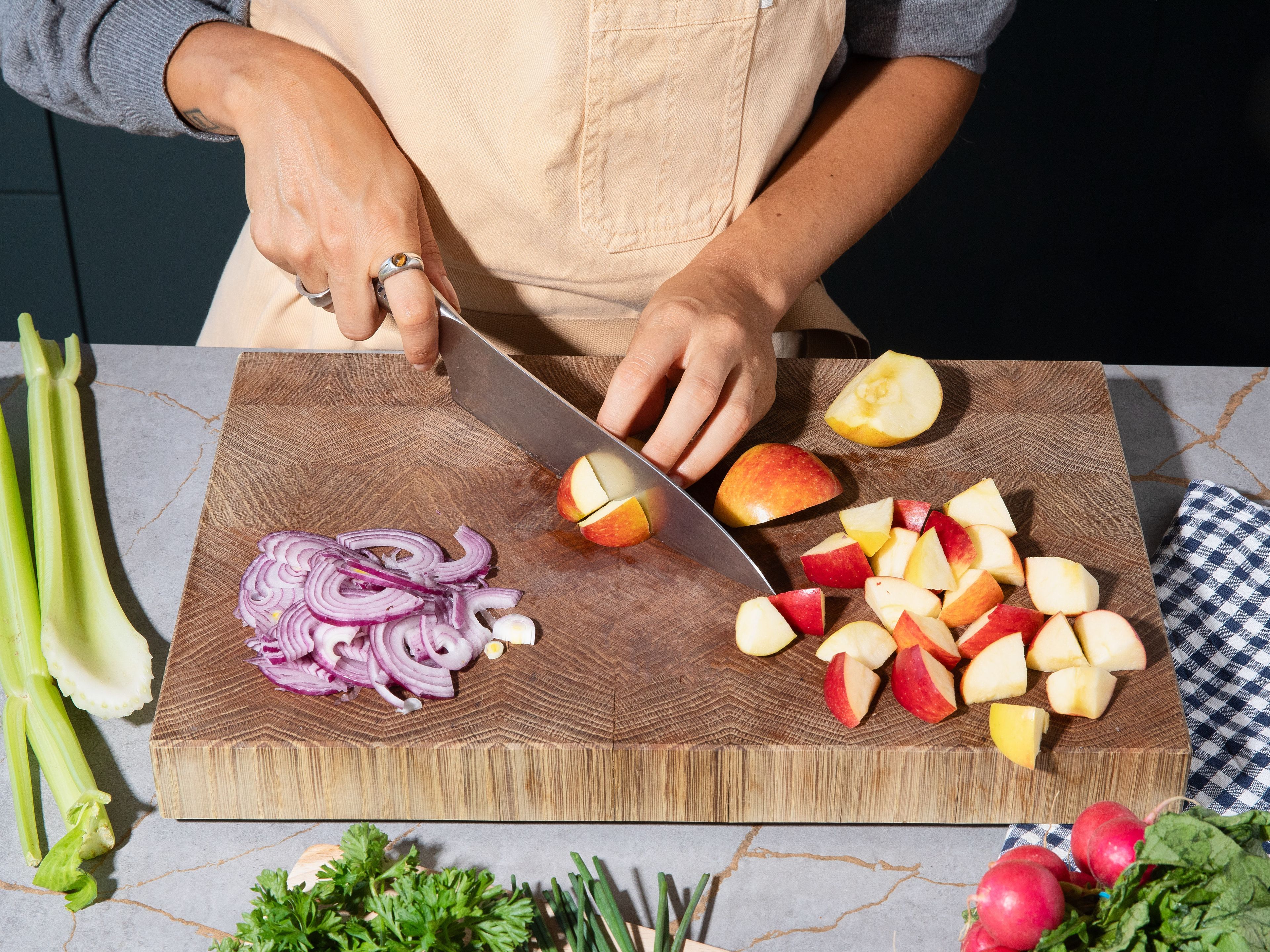 Meanwhile, cut radishes, kohlrabi, celery, and apples into large pieces. Cut red onions into thin half-moons. Cut chives into thin rings and roughly chop parsley. Cut bratwurst into approx. 2 cm / 0.8 in. thick slices and fry in a pan on both sides until golden brown.