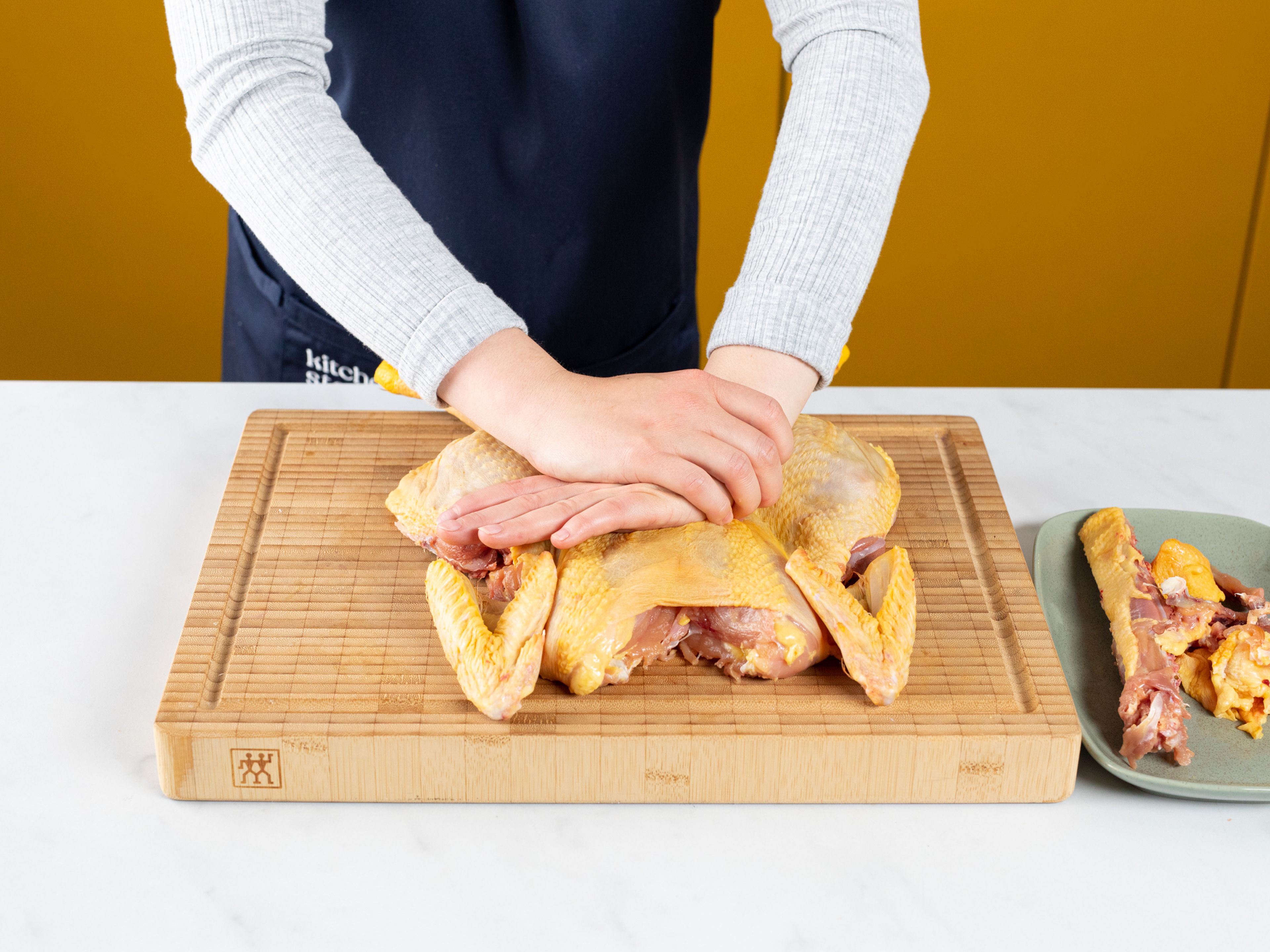 Den Ofen auf 230°C vorheizen. Das Huhn wie in unserem Tutorial plätten und die Wirbelsäule und alle anderen Reste für eine Brühe reservieren, anstatt sie wegzuwerfen. Anschließend die Hähnchenhaut mit Papiertüchern trockentupfen.