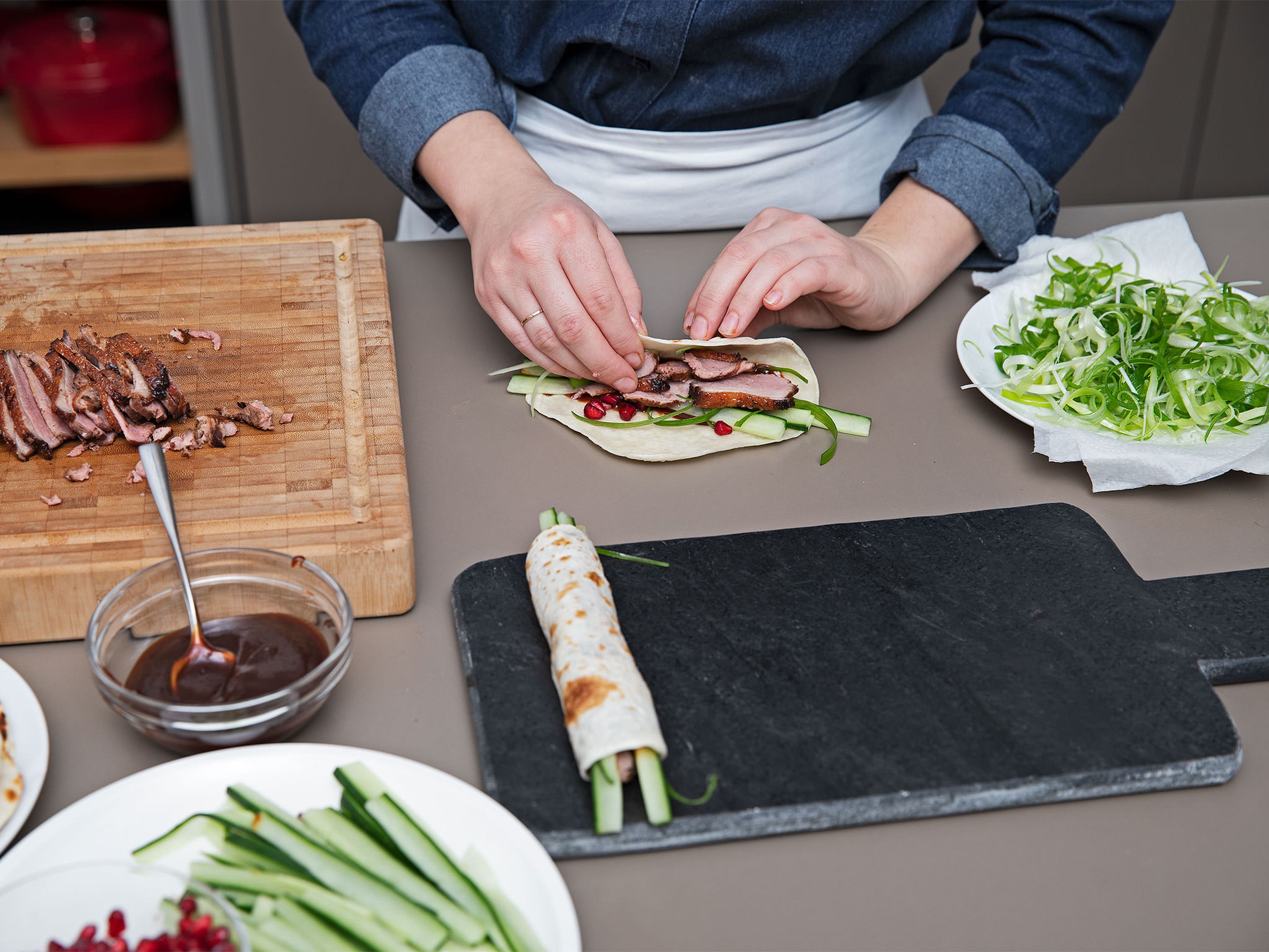 Spread pancakes with hoisin sauce, top with cucumber, scallions, pomegranate seeds, and duck slices, then wrap them one after another. Enjoy!