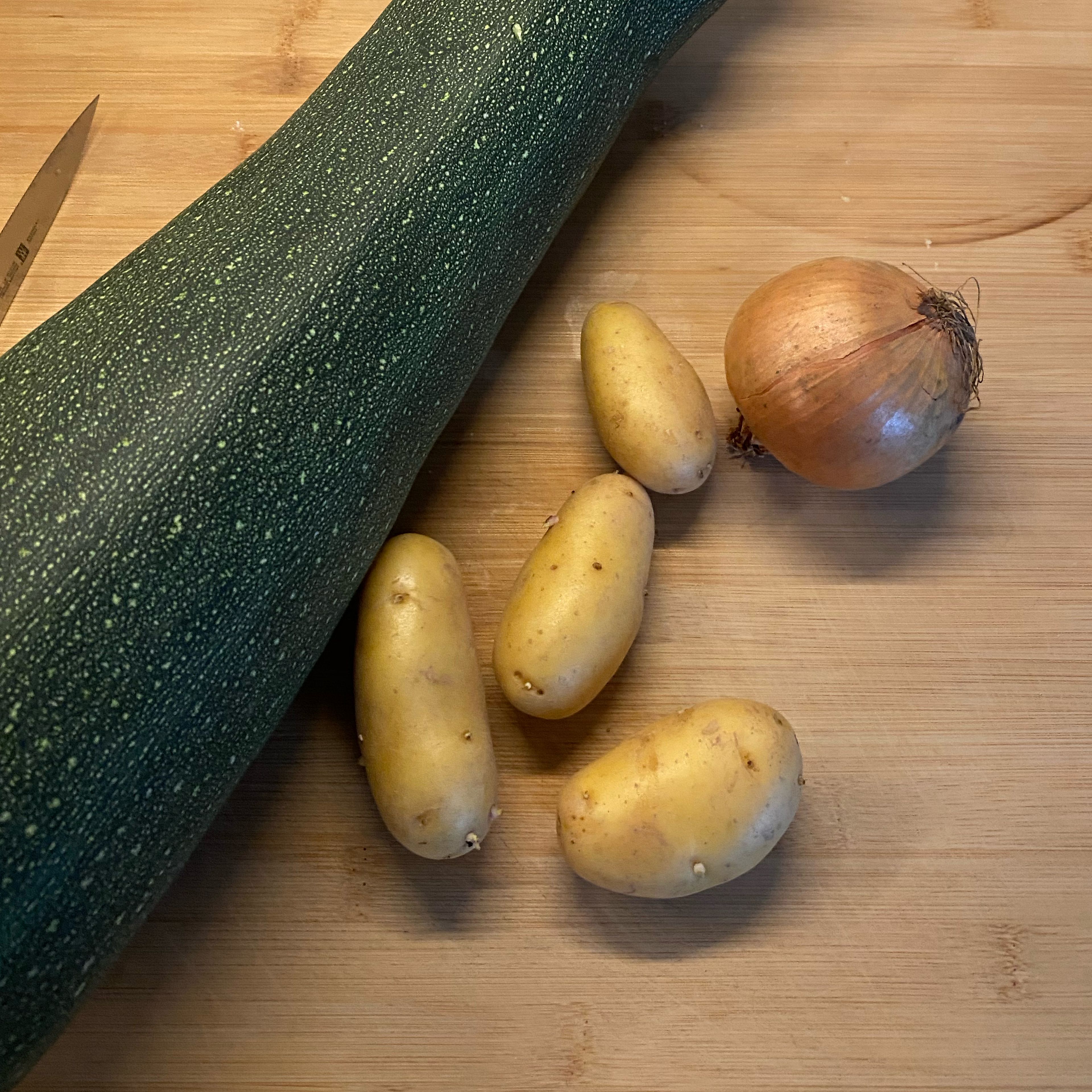 Zucchini waschen und in große Würfel schneiden. Kartoffeln schälen und ebenfalls würfeln. Zwiebel schälen und grob schneiden.