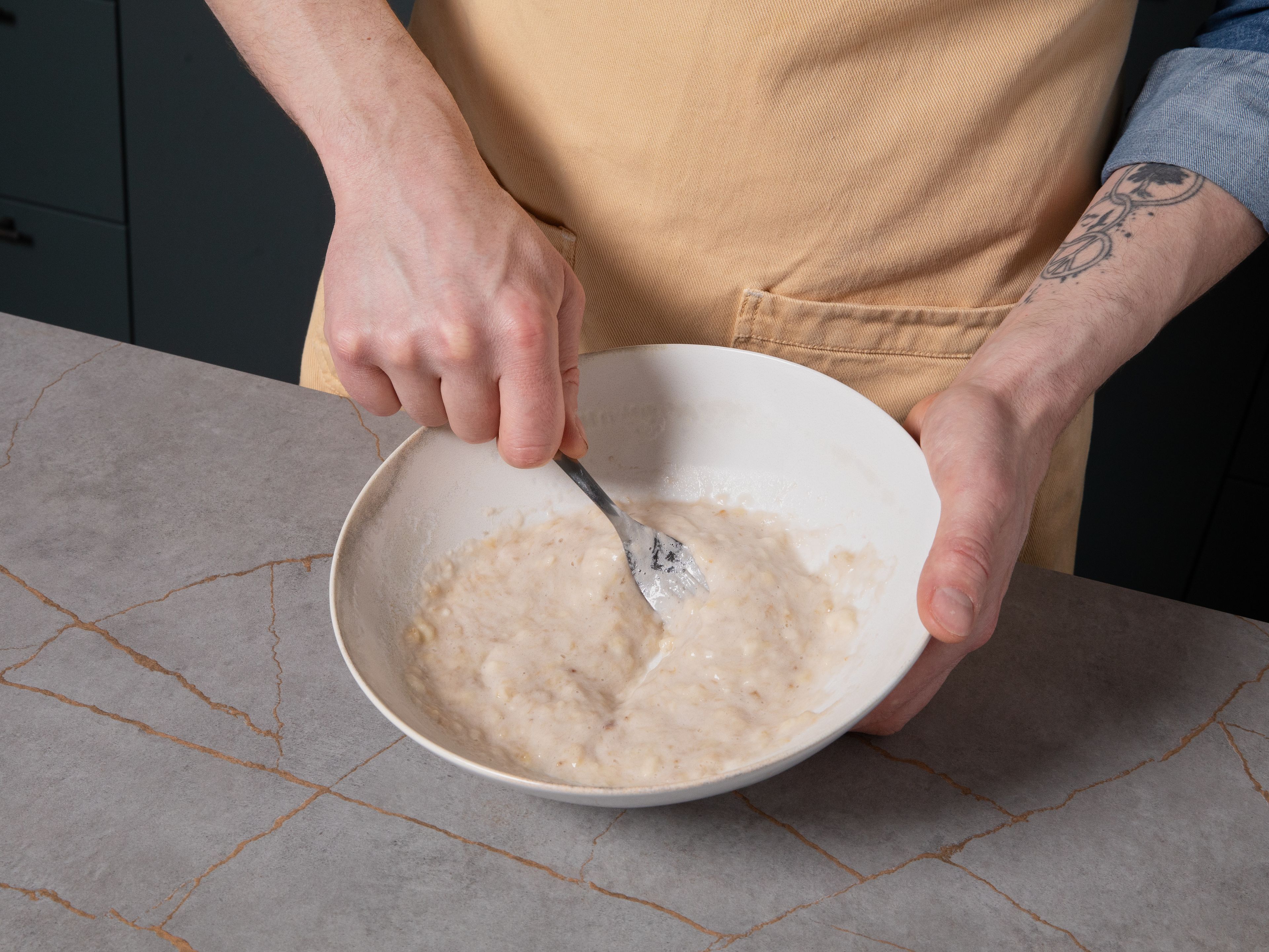For fluffy banana pancakes, mash ripe bananas in a bowl using a fork. Add egg and milk, then whisk everything together until smooth.