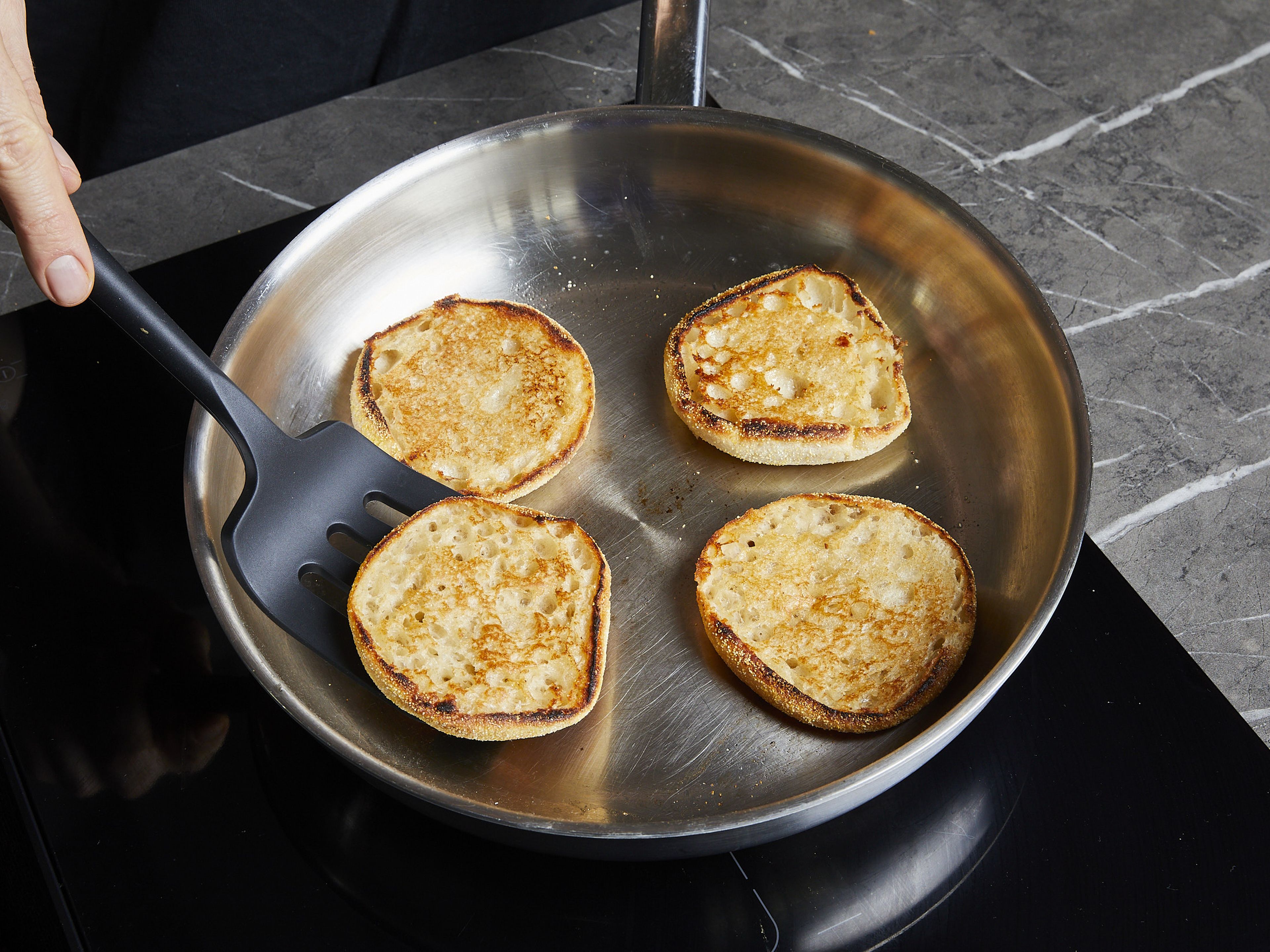 Melt some butter in a large frying pan, cut the English muffins open, toast until golden brown, and set aside.