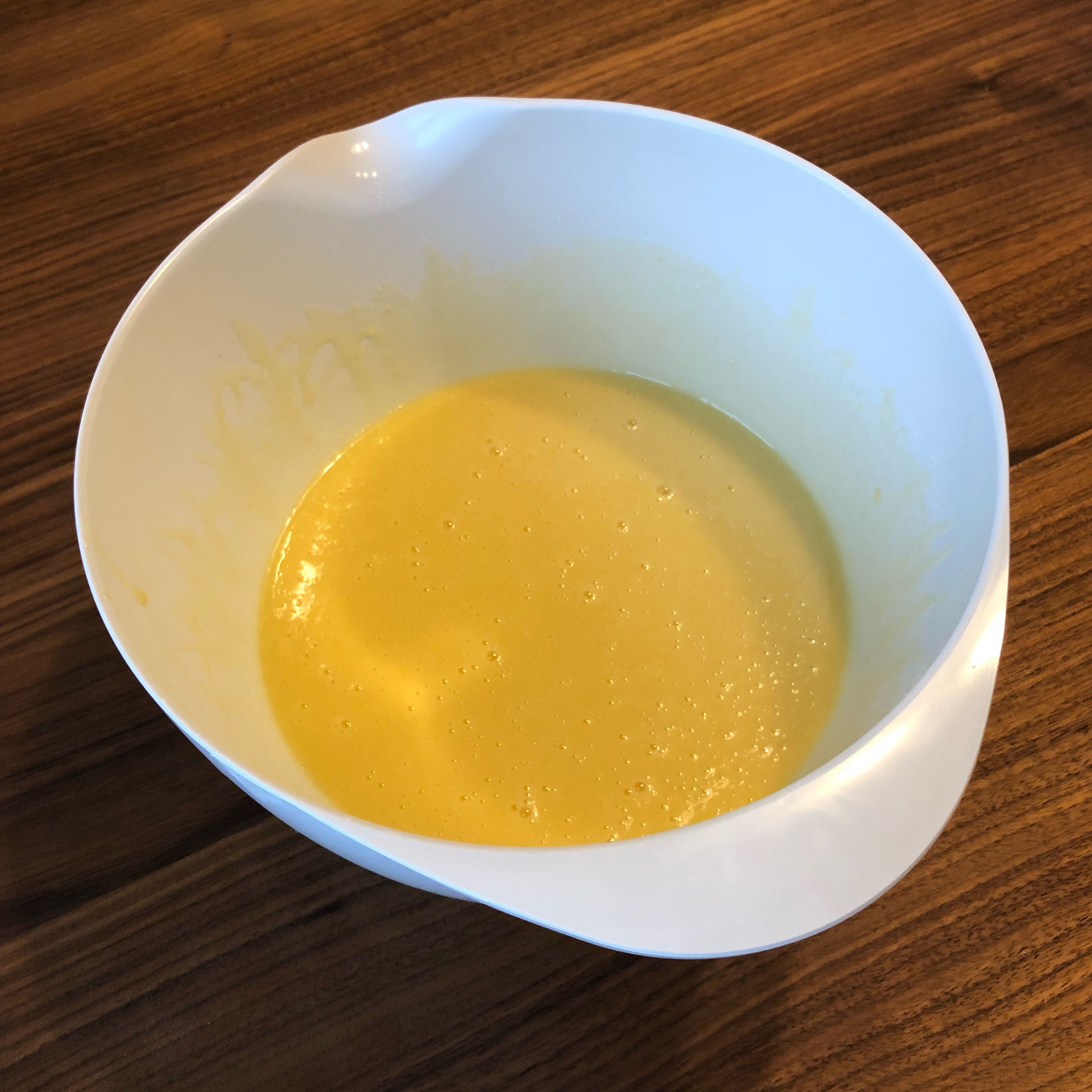 Den Ofen auf 180° vorheizen. Die Butter in einem Topf schmelzen. Danach Eier, Zucker, Backpulver, Vanillezucker, Milch, Weizenmehl und die geschmolzene Butter in eine Rührschüssel geben und zu einem glatten Teig verrühren.