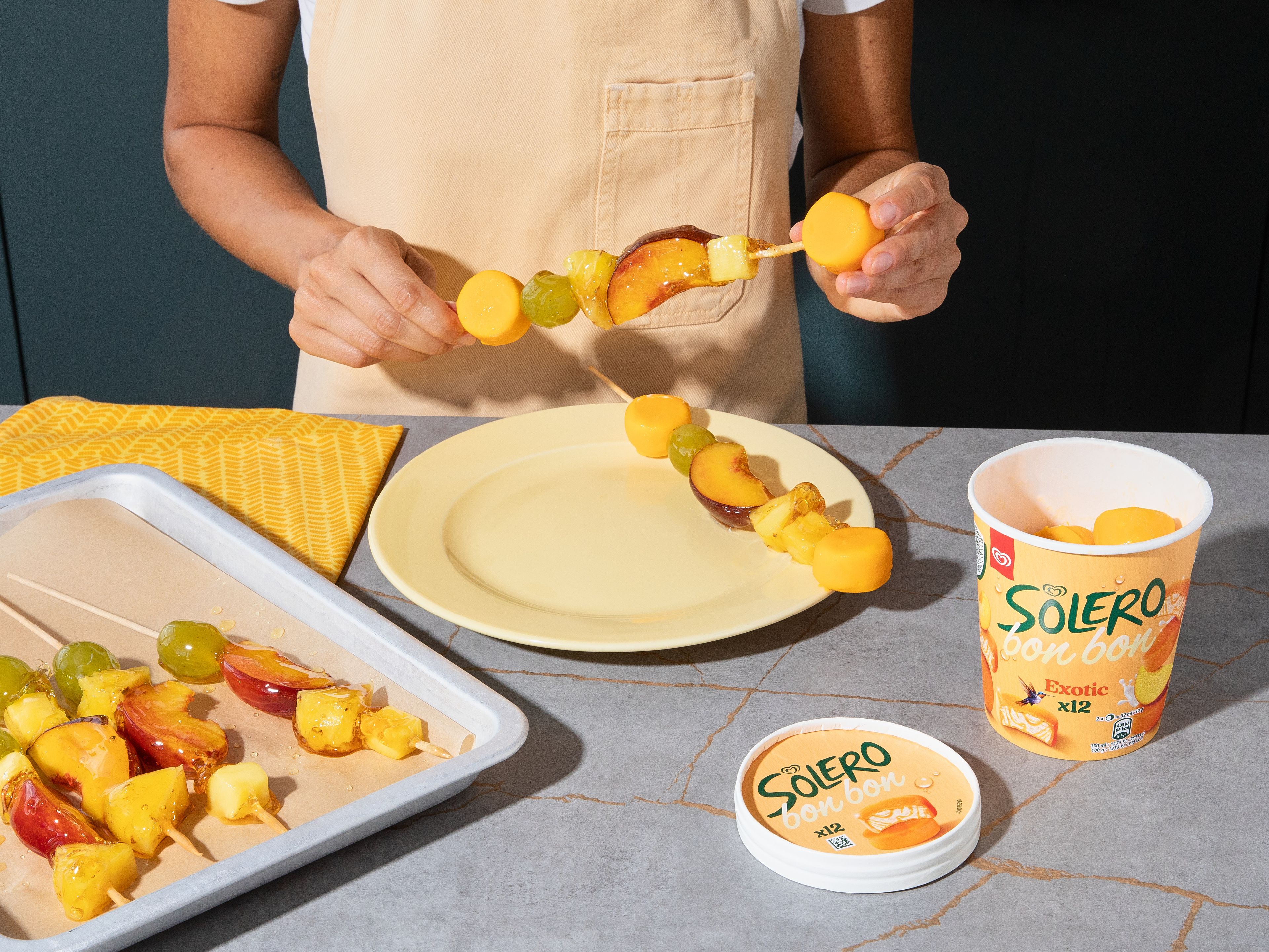 Das Thermometer entfernen. Den Topf leicht neigen, sodass sich der Zucker auf einer Seite sammelt. Die Fruchtspieße zügig hineintauchen, dabei drehen und überschüssigen Zucker abtropfen lassen. Anschließend sofort in das Eiswasser tauchen und auf das vorbereitete Backblech legen. Nach ca. 1 Min. sind die Spieße vollständig ausgekühlt. Dann auf alle Spieße jeweils 2 Solero Bonbons stecken und sofort servieren.