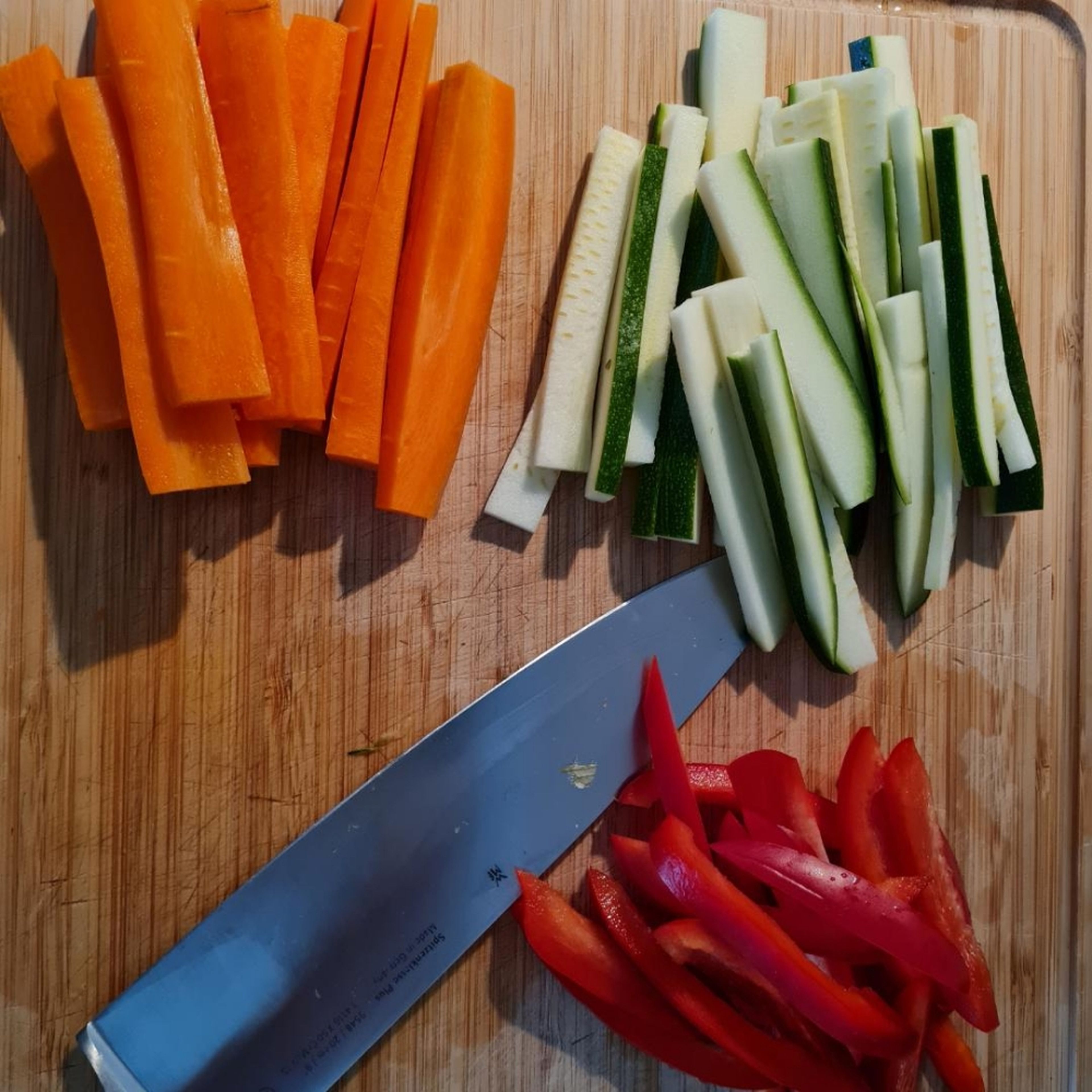 Frühlingszwiebel in kleine Scheiben schneiden. Gemüse in Streifen schneiden. Knoblauch schälen.