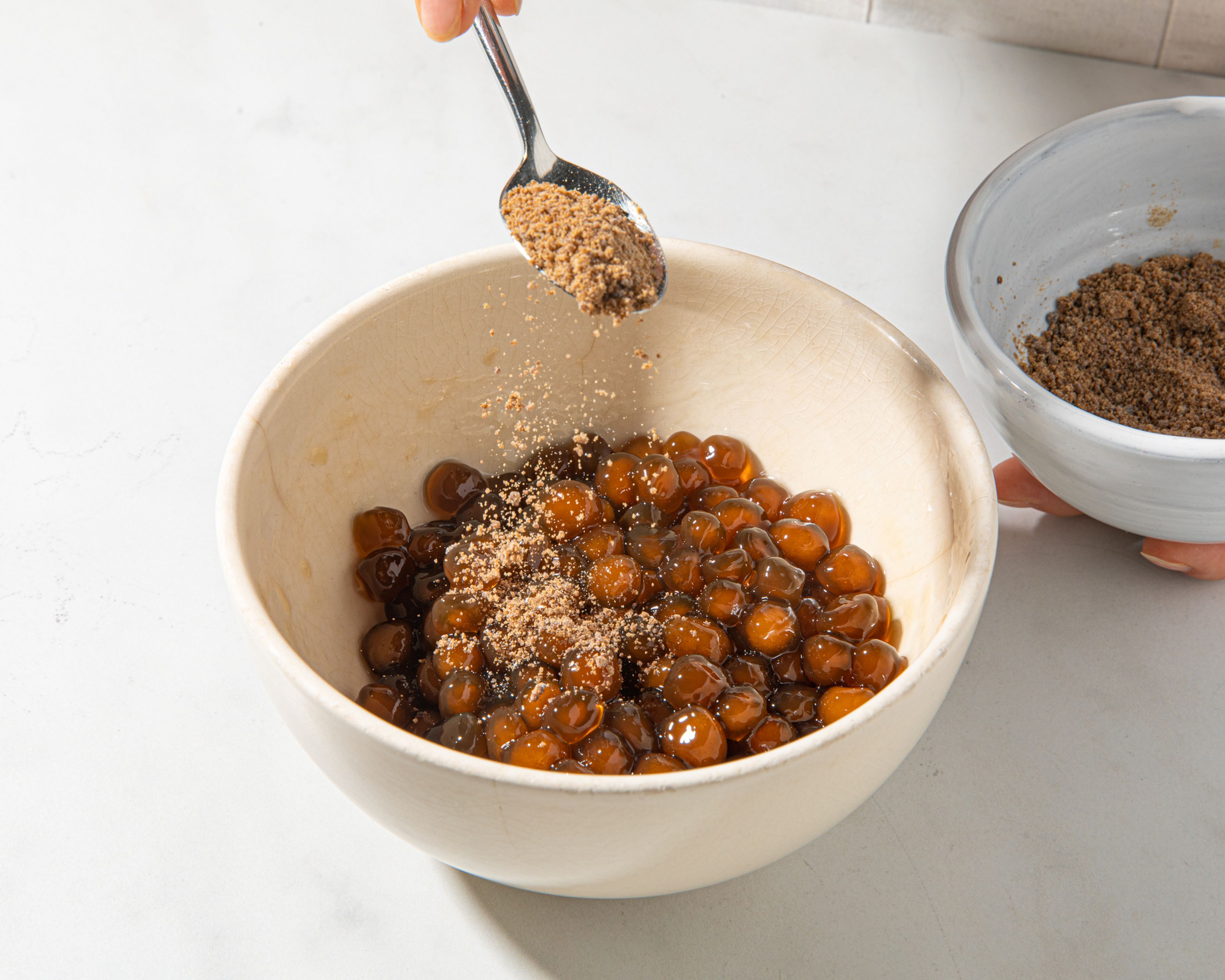 To cook the tapioca pearls, bring a pot of water to a boil. Add the pearls and let them simmer over medium heat for approx. 10 min. Turn off the heat and cover with a lid. Let the pearls rest for approx. 10 min., or until they are cooked through and transparent. Strain the pearls through a sieve, rinse them with cold water and add them to a bowl. To prevent sticking, you can add a few tablespoons of cold water or more brown sugar.