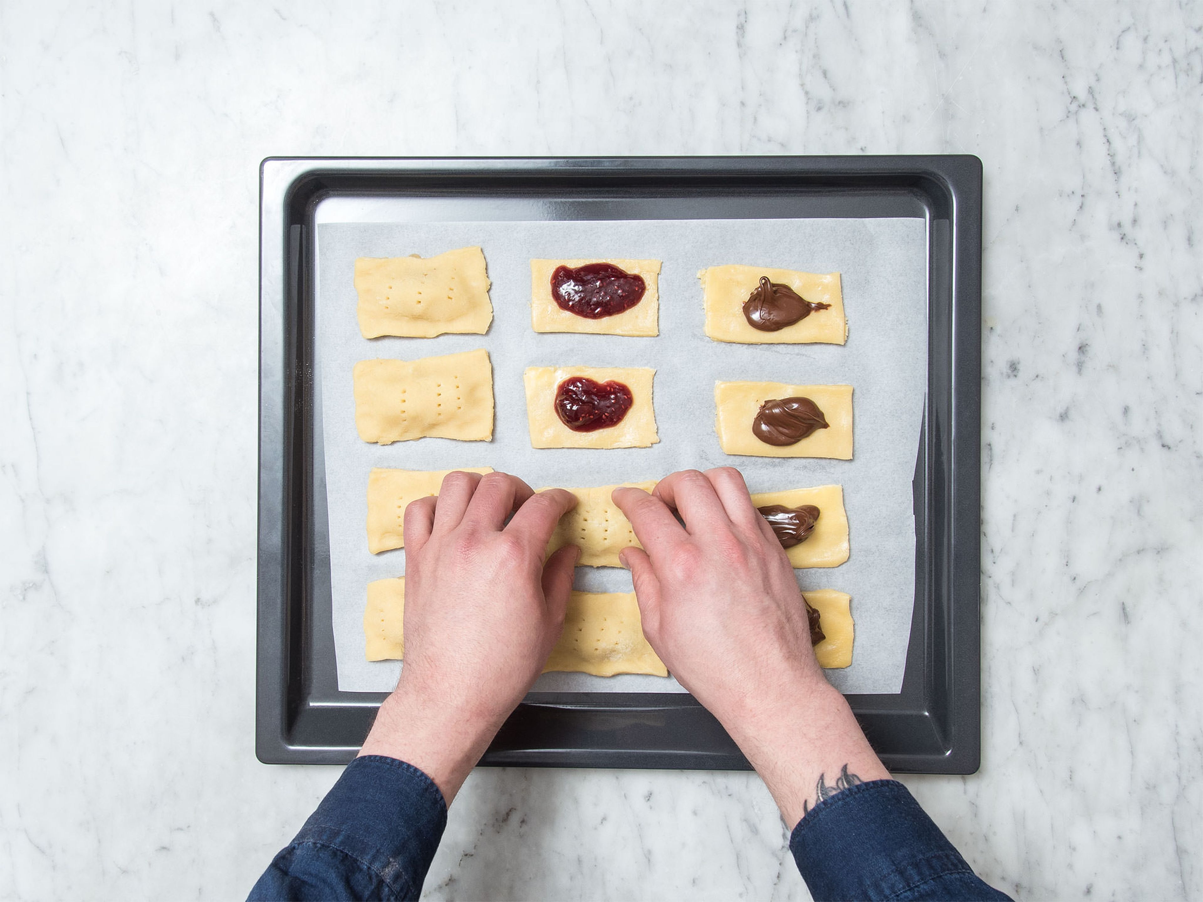 Use a fork to poke holes in the remaining half of the dough, then transfer them onto the filled dough rectangles on the baking sheet. Use your fingertips to press around the filling, then use a fork to seal the edges so the filling will stay inside. Preheat oven to 175°C/350°F and refrigerate pop tarts for approx. 20 min. Afterwards, bake them for approx. 20 min. until golden brown. Let cool.