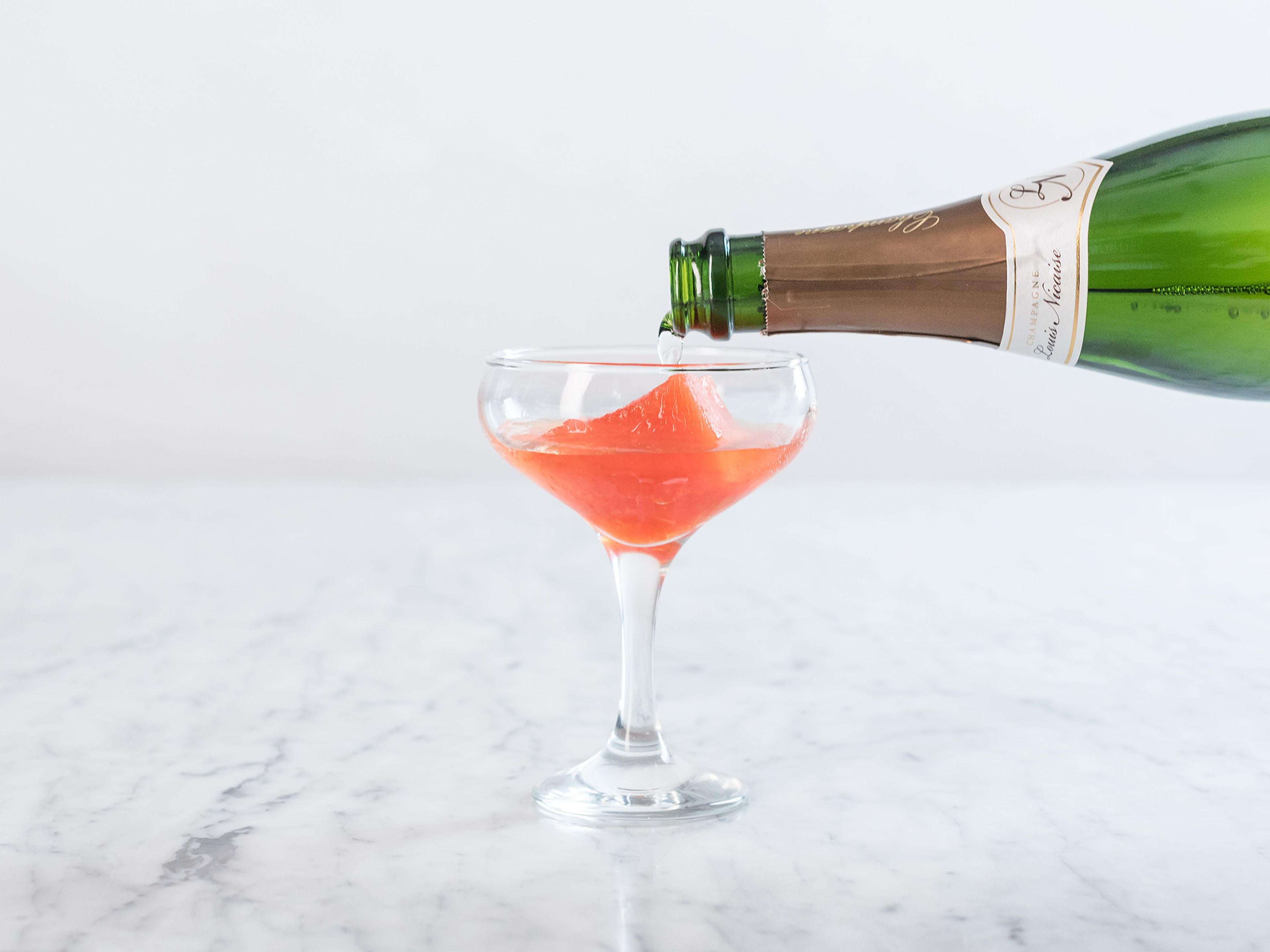 Einen Aperol-Eiswürfel auf jedes Glas verteilen, mit Prosecco auffüllen und mit einer Orangenspalte garnieren. Prost!
