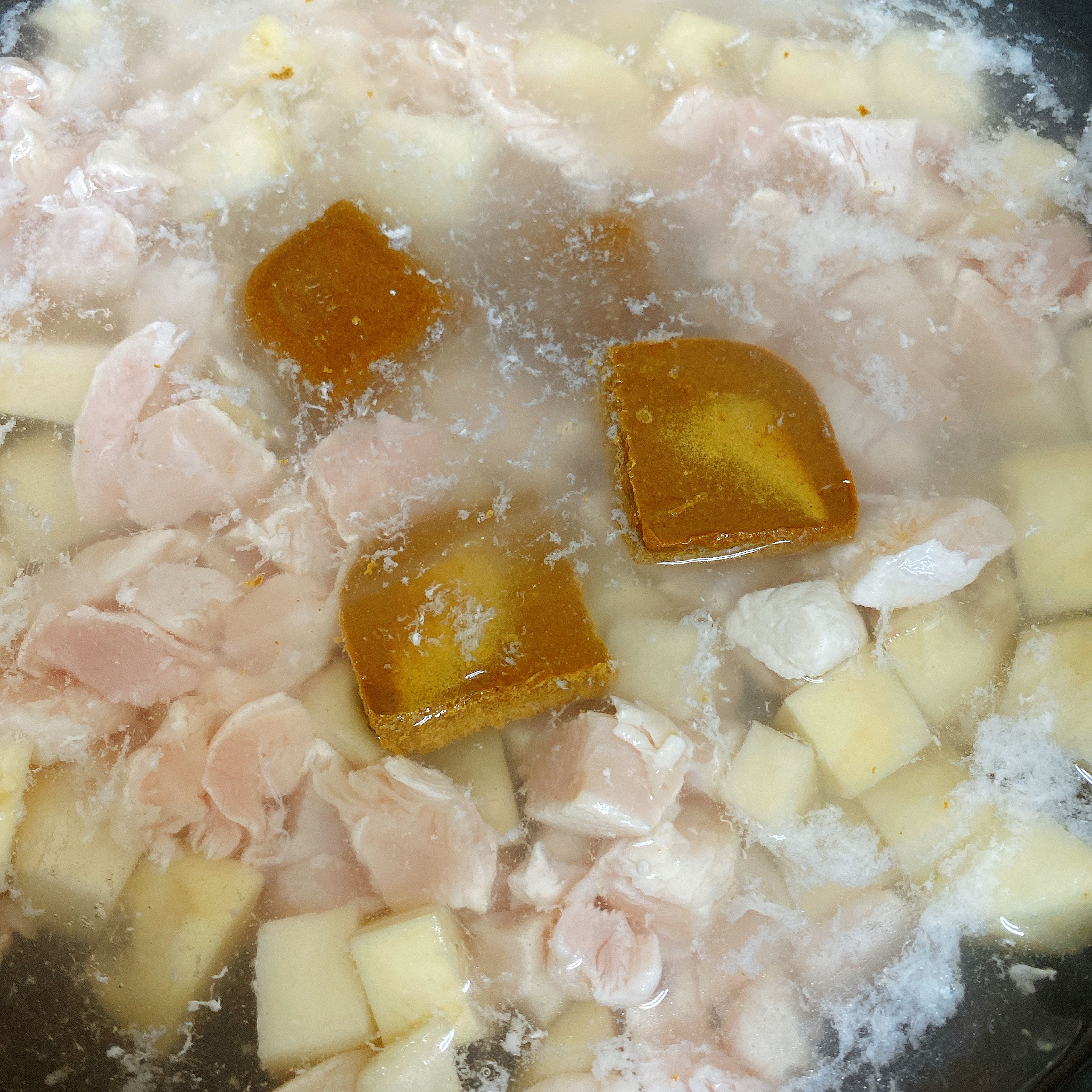 Add cold water to the wok until the ingredients are just fully submerged. Add the curry cubes. Put the lid on and turn the stove to medium when the water starts to boil.