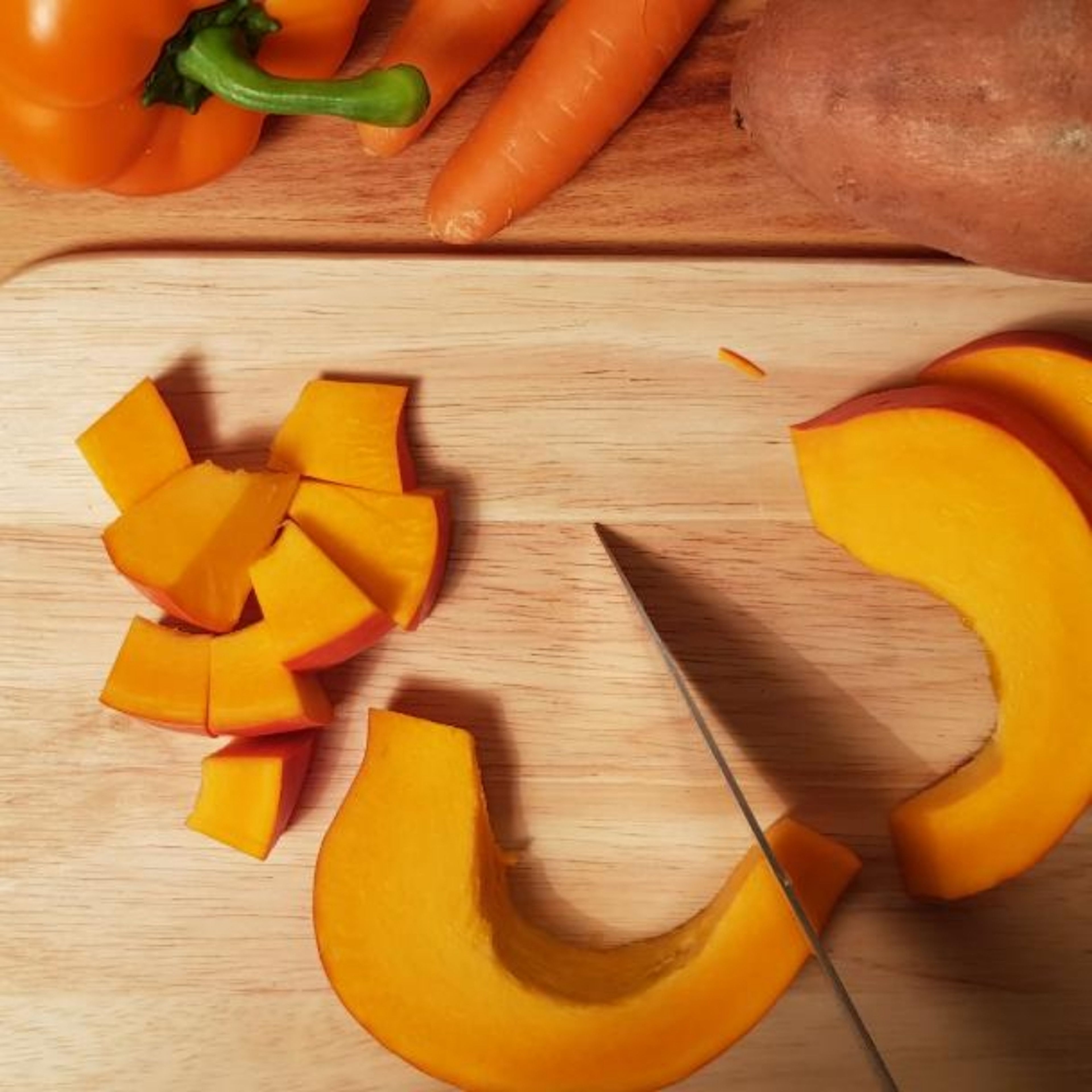 Backofen auf 200° Ober- und Unterhitze vorheizen. Kürbis und Süßkartoffel in etwa 1 cm große Stücke schneiden. Karotten und Paprika in Streifen schneiden. Das geschnittene Gemüse in die Auflaufform geben.
