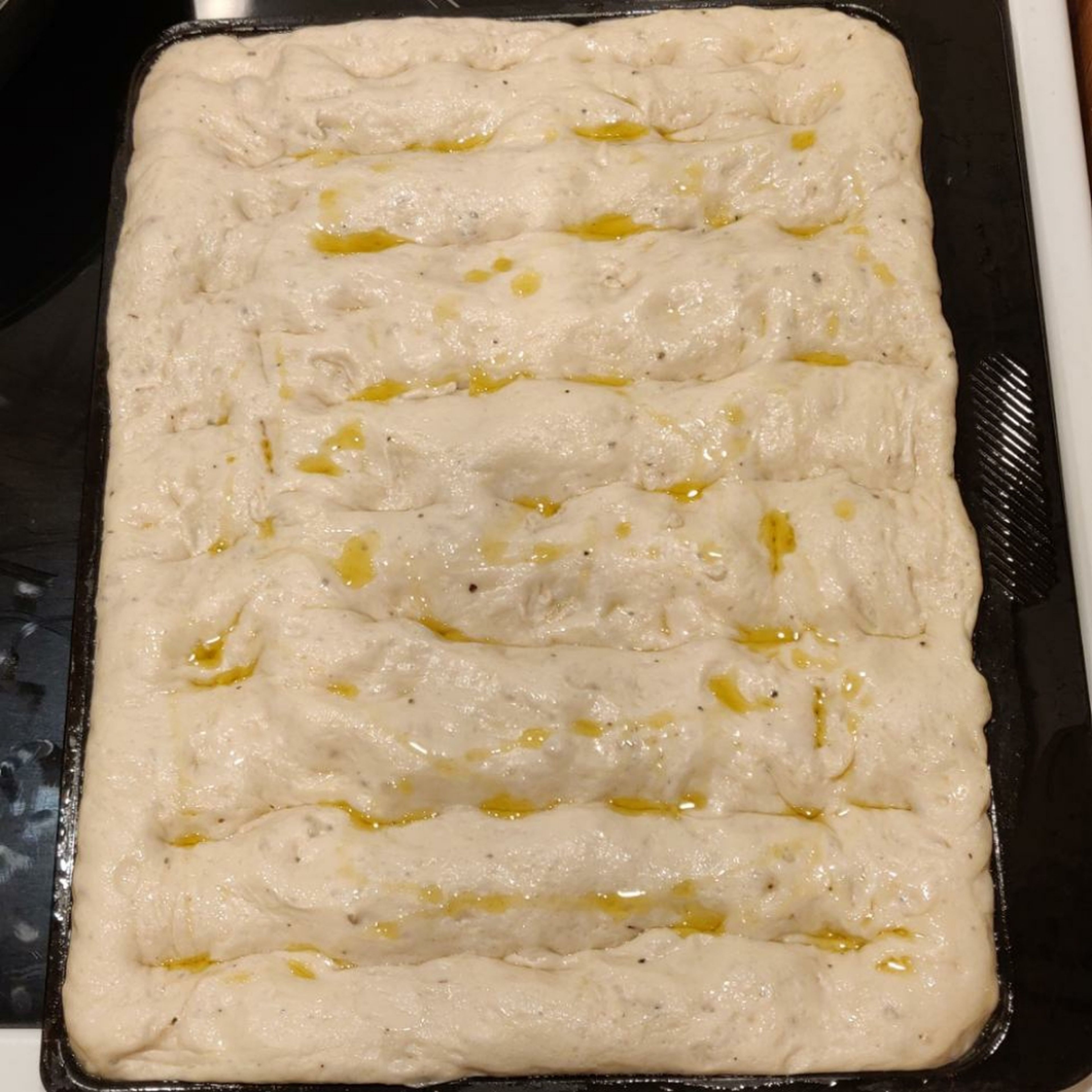 remove the plastic wrap and add the rosemary sprigs on top of the focaccia. you could use garlic, pepper corns, seeds, fennel, sundried tomatoes, etc, for this. drizzle extra olive oil over the top of the focaccia.