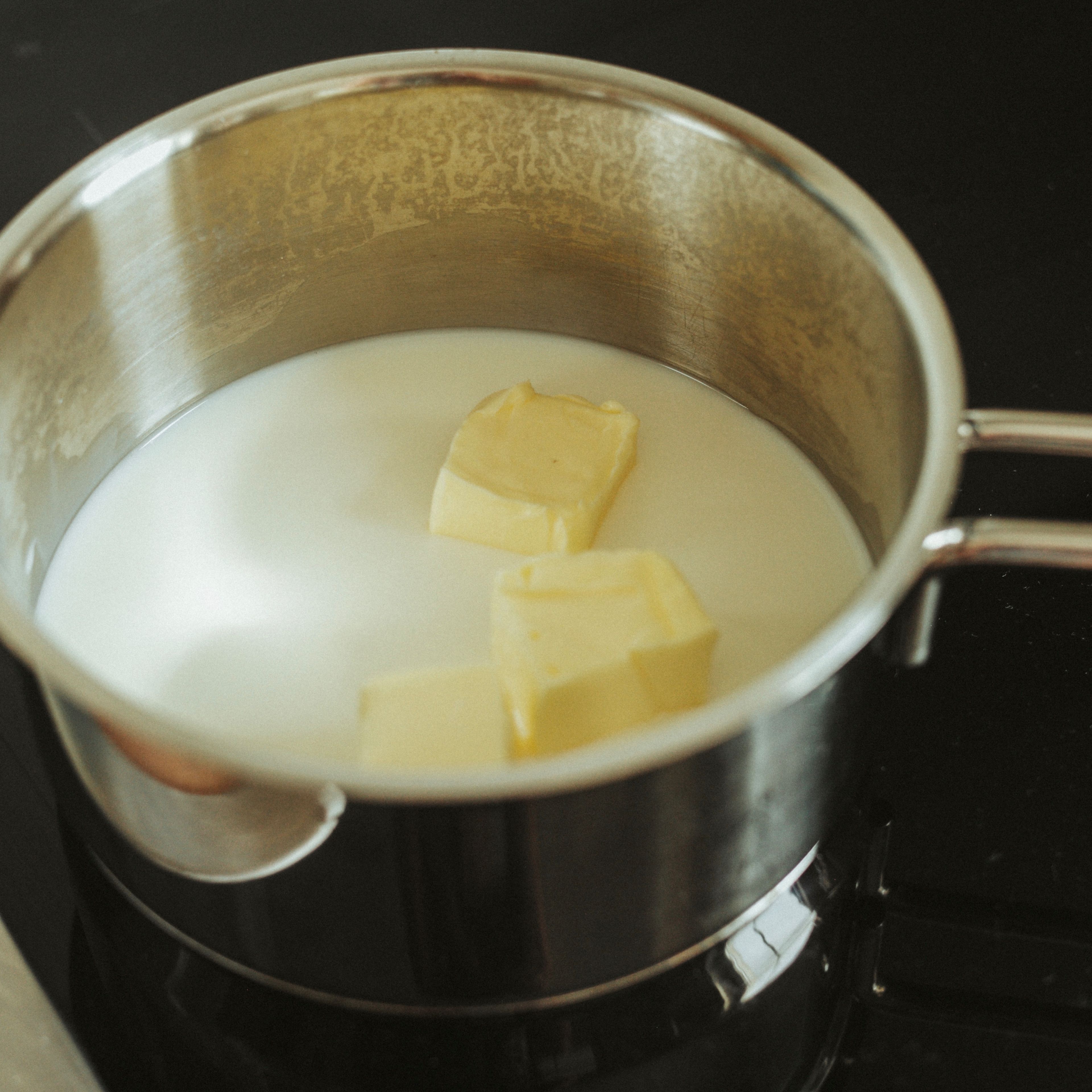 Für den Hefeteig Milch und Butter in einen kleinen Kochtopf geben und auf dem Herd bei schwacher Hitze langsam erwärmen, bis die Milch lauwarm und die Butter geschmolzen ist. Die Milch-Butter-Masse in eine Schüssel geben.