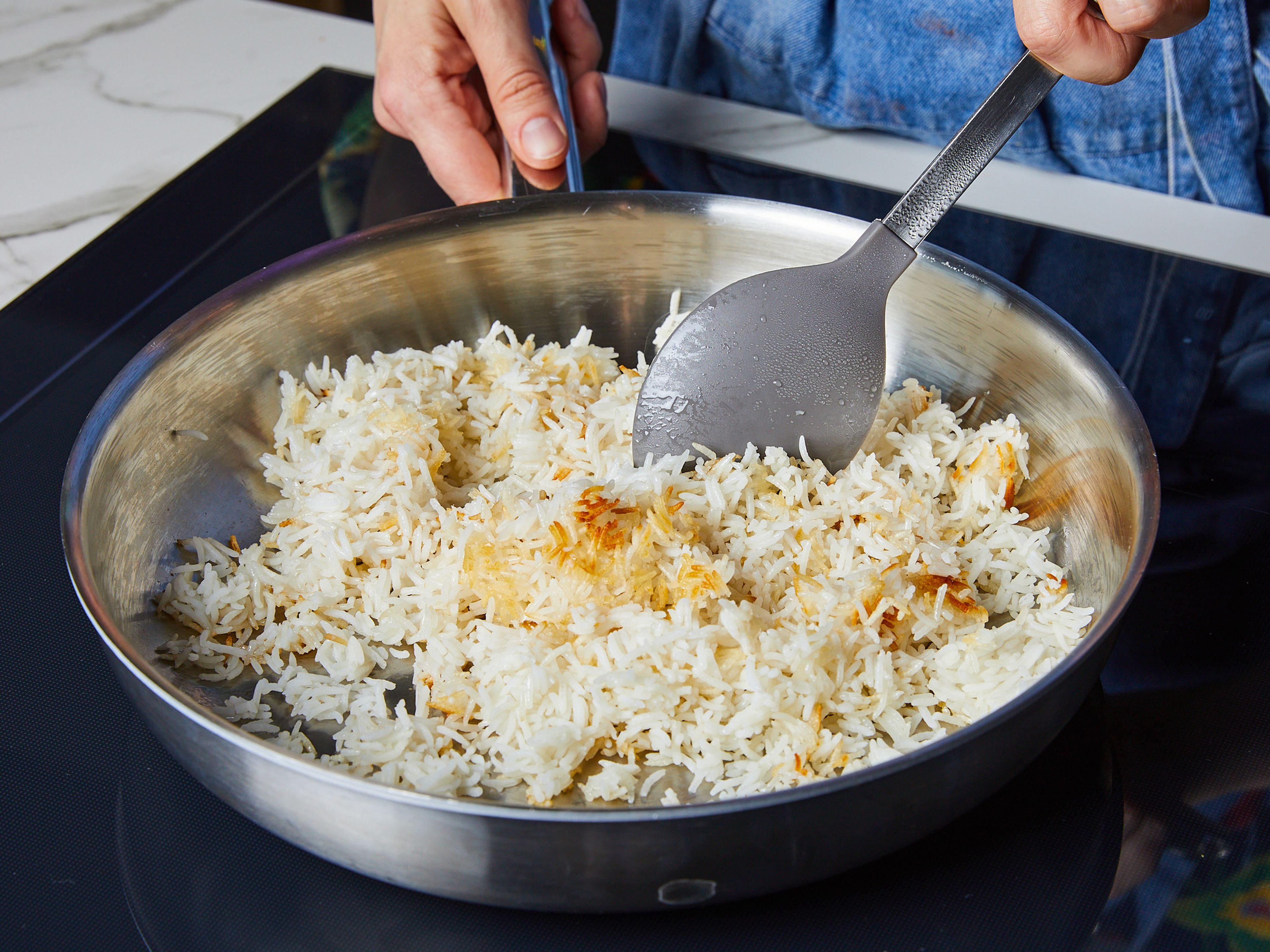 In der Zwischenzeit ein weiteres ¼ des Öls in einer Pfanne erhitzen, den gekochten Reis hinzugeben und unter Rühren bei starker Hitze ca. 7–10 Min. braten, bis der Reis knusprig und goldbraun ist. Darauf achten, dass die Reiskörner nicht zerdrückt werden. Dann das Gemüse auf das Backblech geben und alles weitere 8–10 Min. backen.