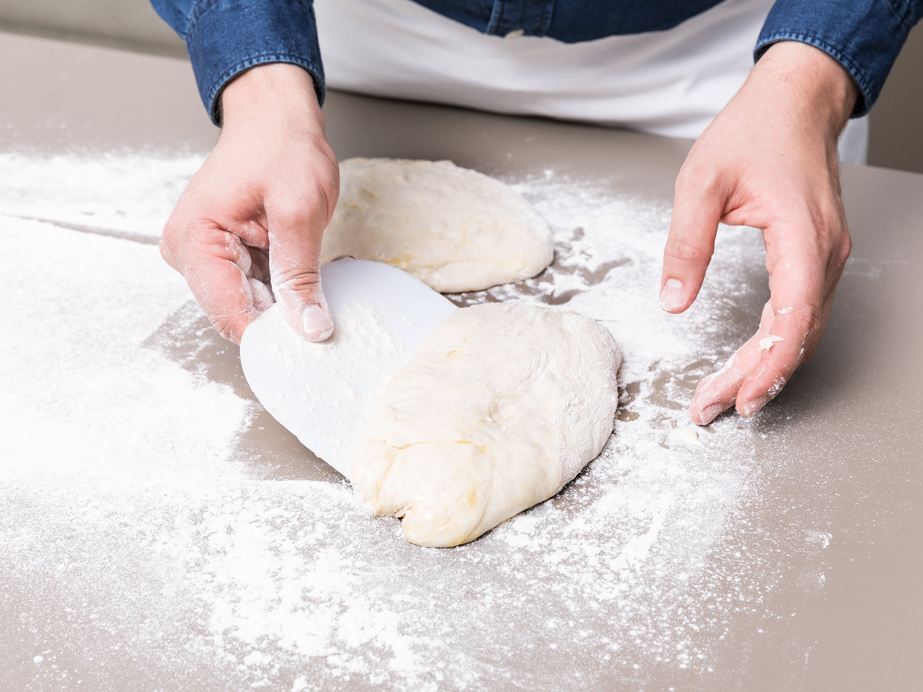 Transfer dough to a floured work surface, sprinkling with more flour as needed. Pat the dough and use a bench scraper to help fold it into thirds a few times. Transfer to a greased baking sheet and cover with plastic. Let rest at room temperature until it has doubled in size, approx. 1 – 2 hrs.