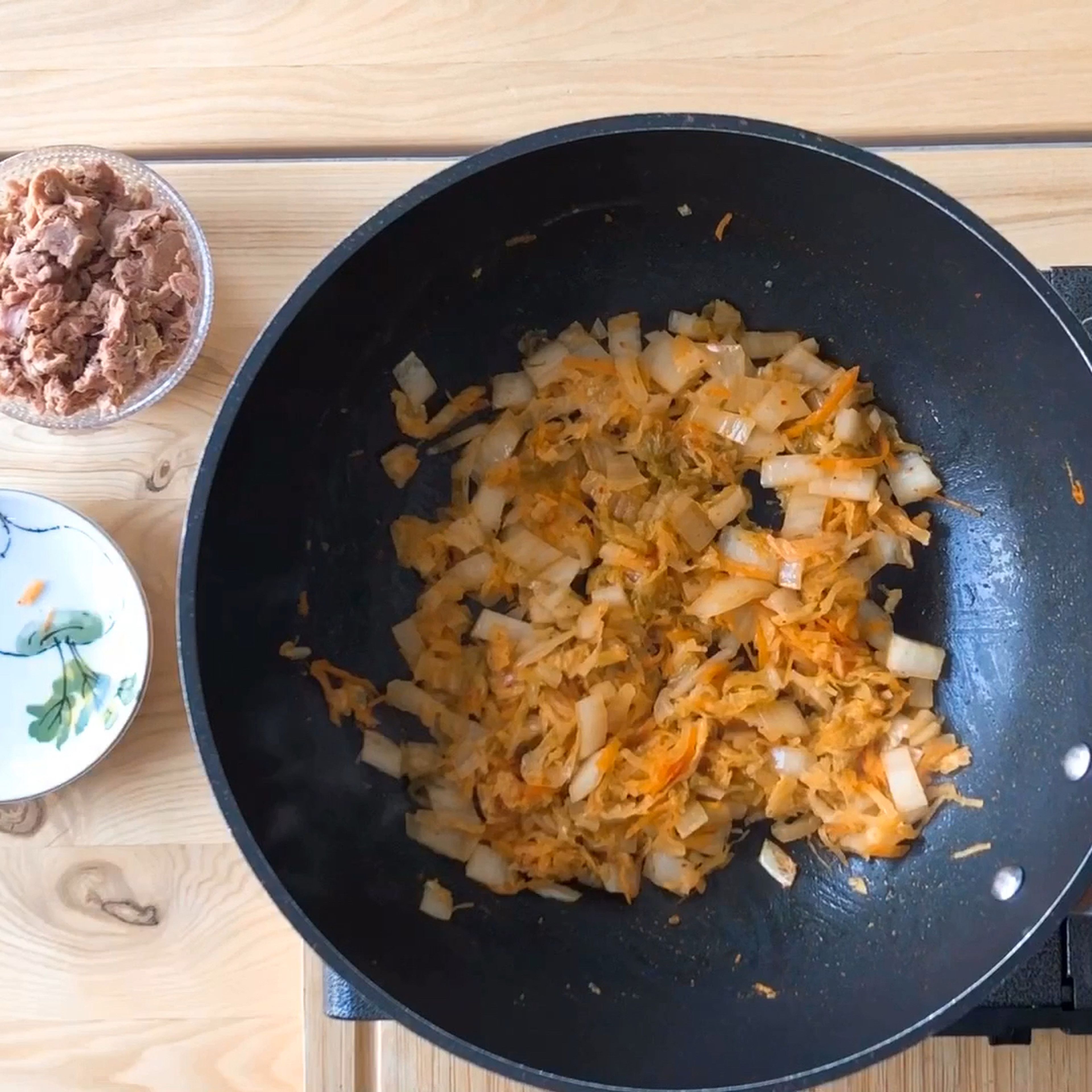 Now we’ll prepare the kimchi. Cut the kimchi into bite-sized pieces, about 1 cm thick, and drain the can of tuna (preferably tuna canned in oil). Heat the butter in a large pan or wok and then add the kimchi. It’s important to use real butter because it gives this dish an added layer of flavor. Let the kimchi fry on medium heat until it becomes translucent, about 5 minutes. Then add the tuna and let it fry for a few more minutes.