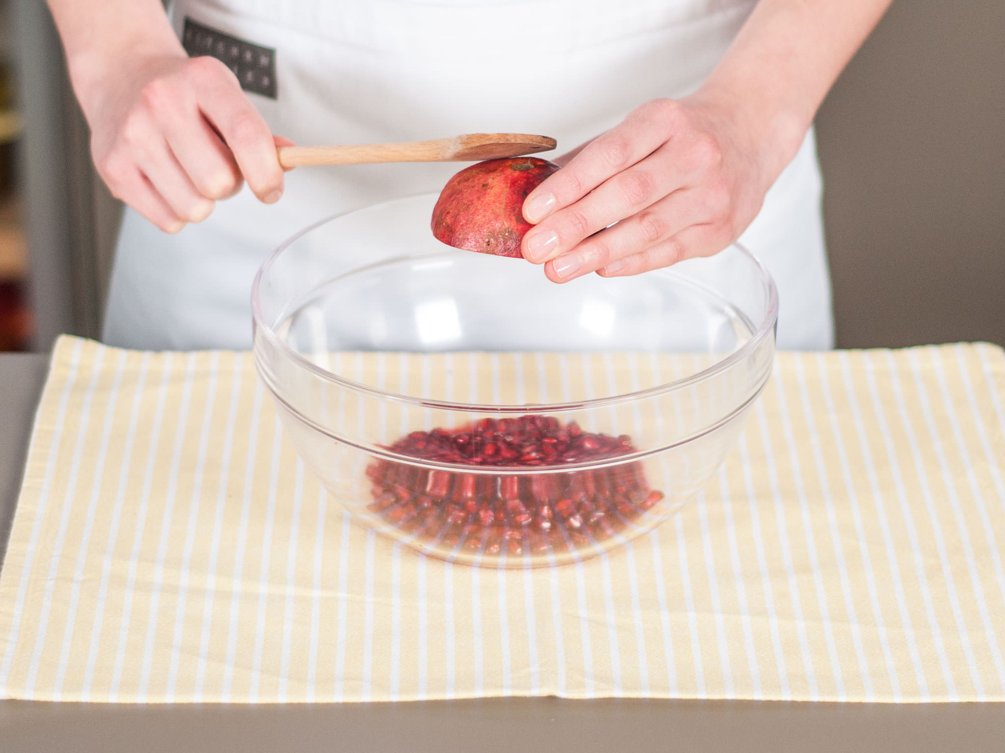 Remove pomegranate seeds and add to large bowl. For easy seed removal, first roll pomegranate on counter to loosen seeds, cut in half, and hold each half over the bowl while tapping firmly with wooden spoon.
