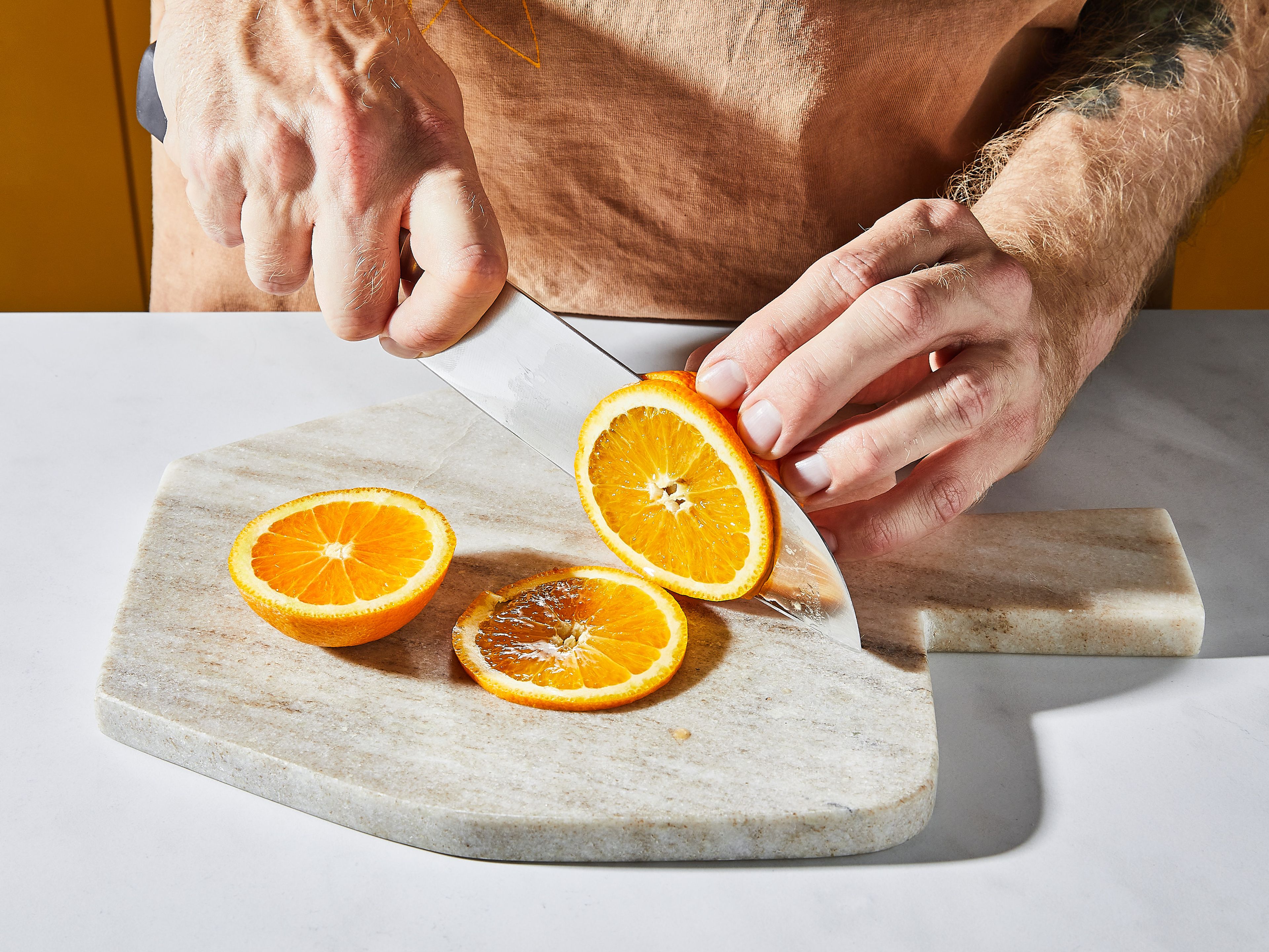 Orange unter heißem Wasser waschen, abtrocknen und 2 dünne Scheiben schneiden. Oliven auf einen Zahnstocher spießen.