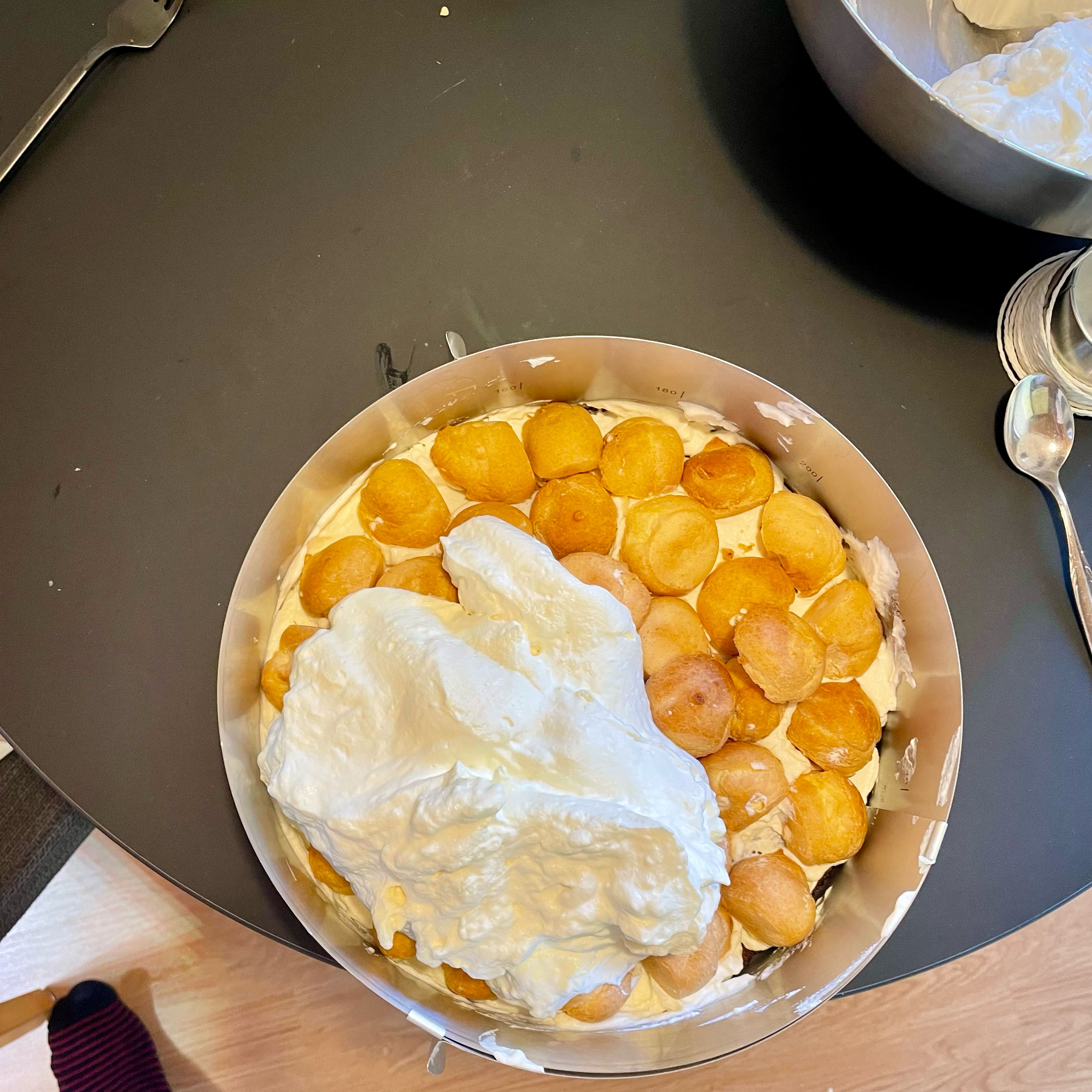 Die gefrorenen Windbeutel halbieren und auf die Creme setzen, die restliche Creme über die Windbeutel streichen und 2-3 Stunden im Kühlschrank kaltstellen.