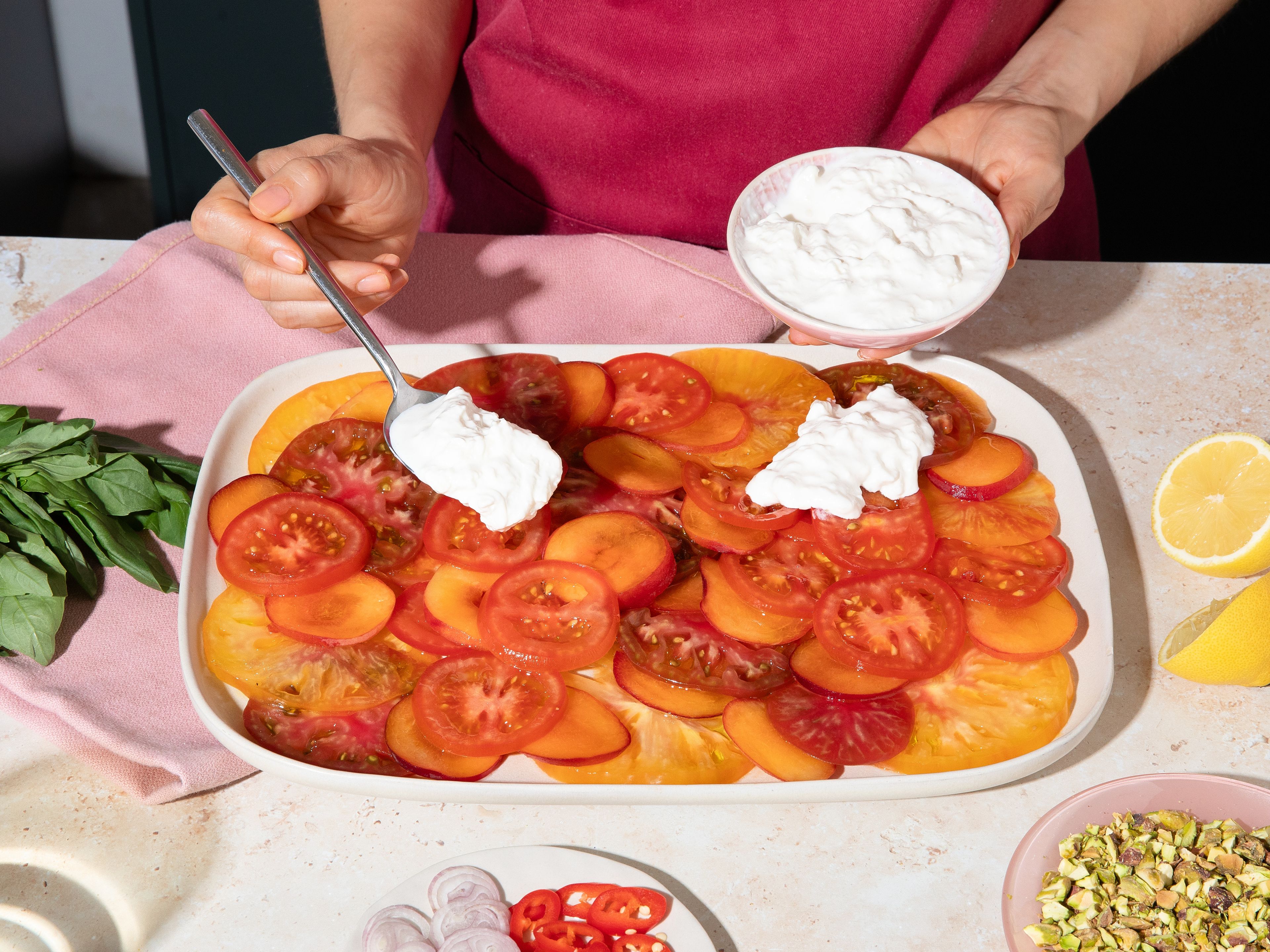 Das Tomaten-Aprikosen-Carpaccio mit Olivenöl und großzügig mit Zitronensaft beträufeln. Stracciatella in Klecksen darauf setzen. Mit Pistazien, Schalotten, Chili, und Basilikum toppen. Zitronenabrieb, Salz und Pfeffer darüber geben und sofort servieren.