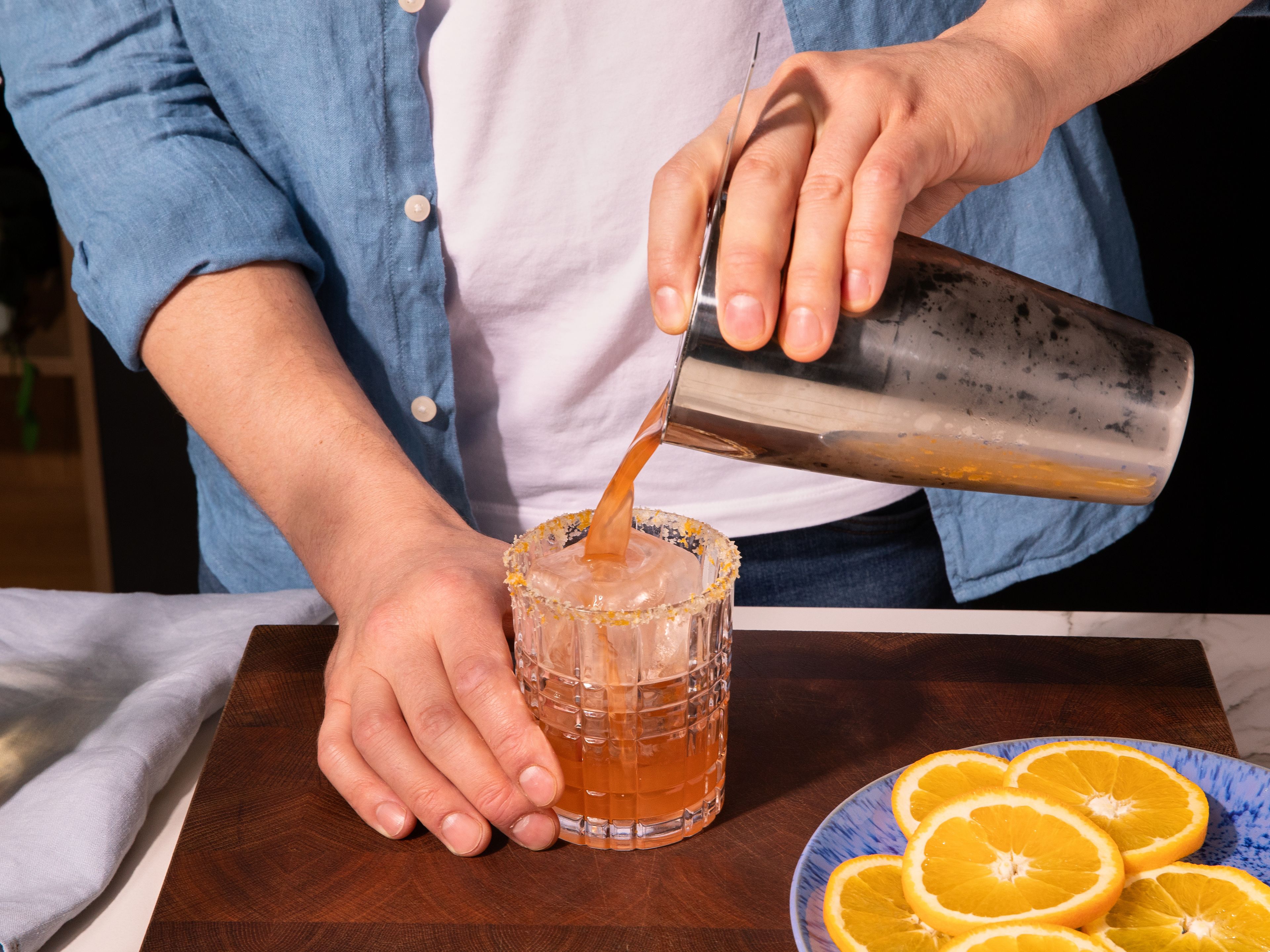 Frische Eiswürfel in das vorbereitete Glas geben, den Drink durch ein Sieb hineingießen, mit einer Orangenscheibe garnieren und sofort eiskalt genießen.