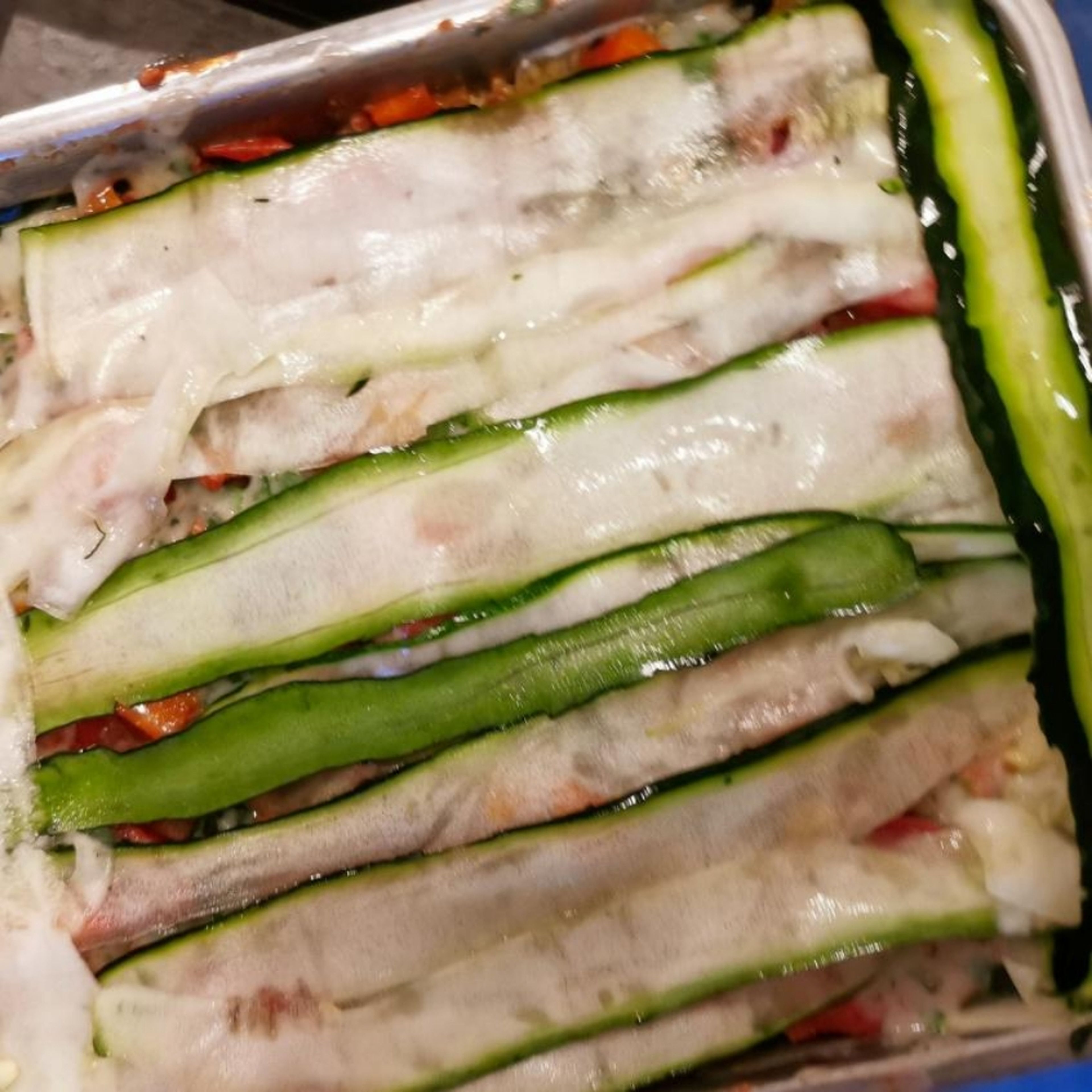 Layer a baking dish with a layer of zucchini followed by minced meat mixture and béchamel sauce.