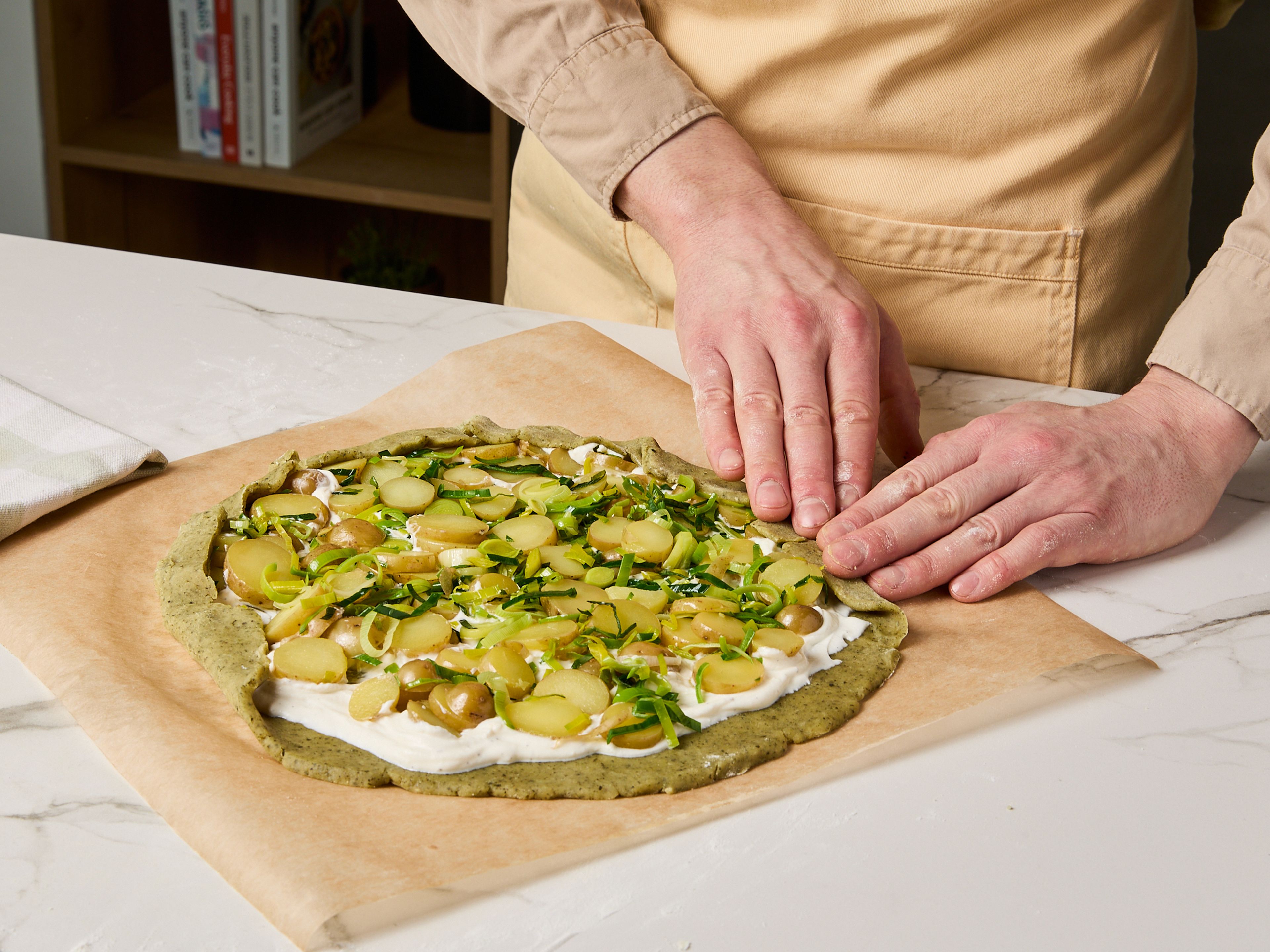 Knoblauch schälen und fein hacken. In einer kleinen Schüssel Ziegenfrischkäse und Sahne mit dem Knoblauch glatt rühren. Mit Salz und Pfeffer abschmecken. Das Ei trennen und in einer kleinen Schüssel Eigelb mit Kürbiskernöl und 1 EL Wasser verrühren. Den Teig auf einer leicht bemehlten Arbeitsfläche zu einem Kreis von ca. 30 cm Durchmesser ausrollen. Die Ziegenfrischkäse-Mischung darauf verstreichen, dabei einen Rand von 2–3 cm aussparen. Das Gemüse auf der Frischkäse-Creme verteilen. Die Teigränder einklappen und dabei leicht überlappen lassen.