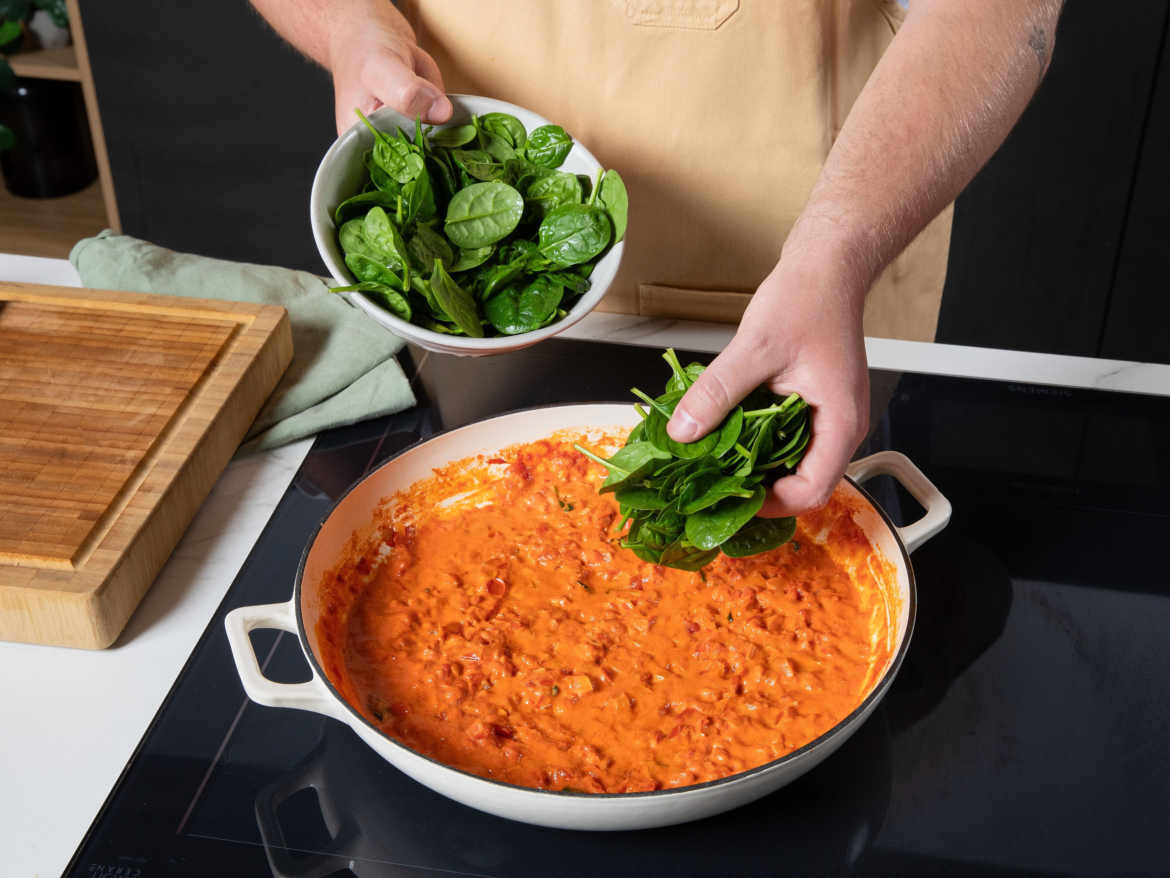 Den Ofen auf 200 °C Ober-/Unterhitze vorheizen. Zwiebel und Knoblauch schälen und fein würfeln. Olivenöl in einer ofenfesten Pfanne erhitzen, Zwiebel und Knoblauch darin glasig dünsten, Tomaten aus der Dose und frischen Oregano hinzufügen und kurz köcheln lassen. Sahne einrühren, frischen Spinat portionsweise unterheben, bis er zusammenfällt, und die Soße mit Salz und Pfeffer abschmecken.