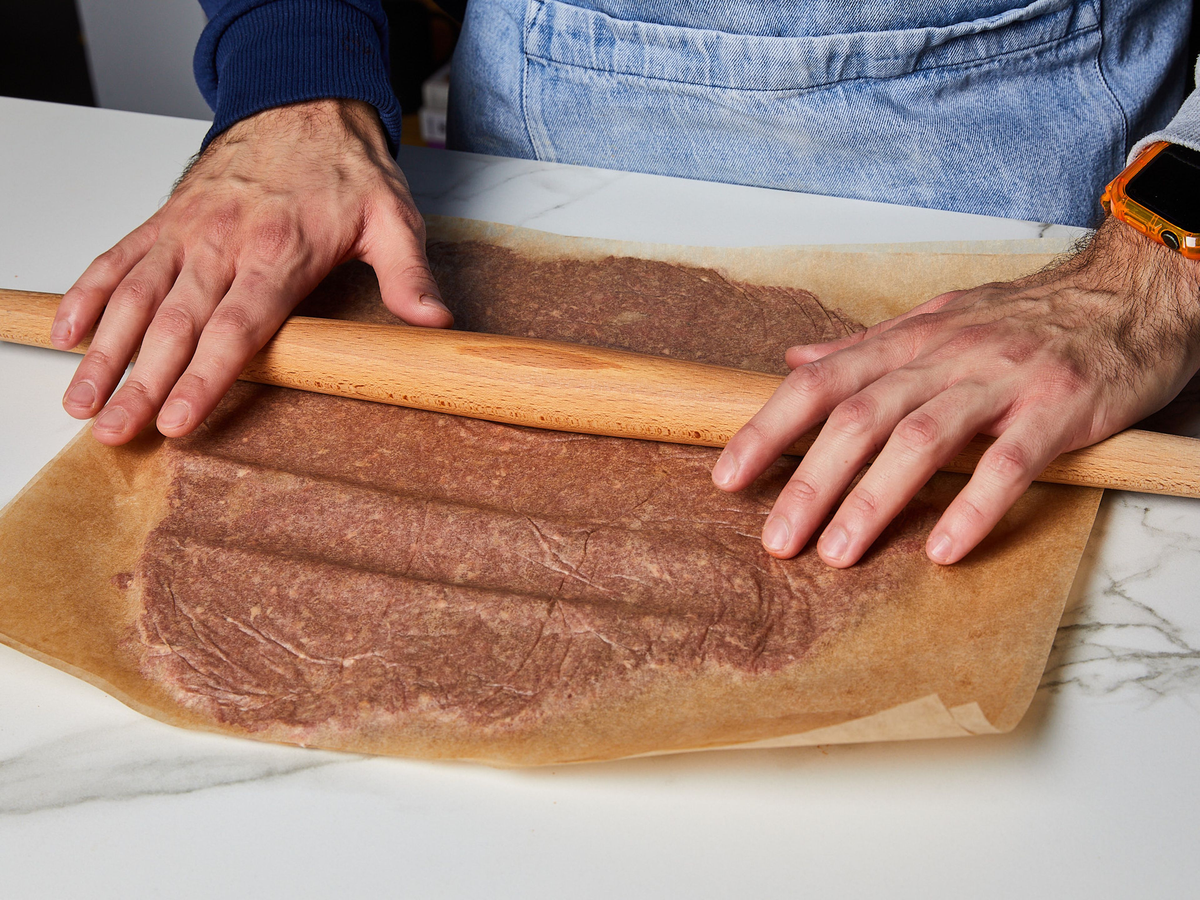 Zuerst die Zwiebel schälen und reiben. Dann das Hackfleisch in eine Schüssel geben. Natron, Salz, Pfeffer, gemahlenen Kreuzkümmel und die geriebene Zwiebel hinzugeben. Alles gut vermengen, dann die Schüssel fest mit Frischhaltefolie abdecken und für ca. 2 Std. oder länger im Kühlschrank durchziehen lassen. Danach das Hackfleisch noch einmal durchmischen und zwischen zwei Backpapierstücke legen. Mit einem Nudelholz ausrollen und in gleich große Stücke schneiden.