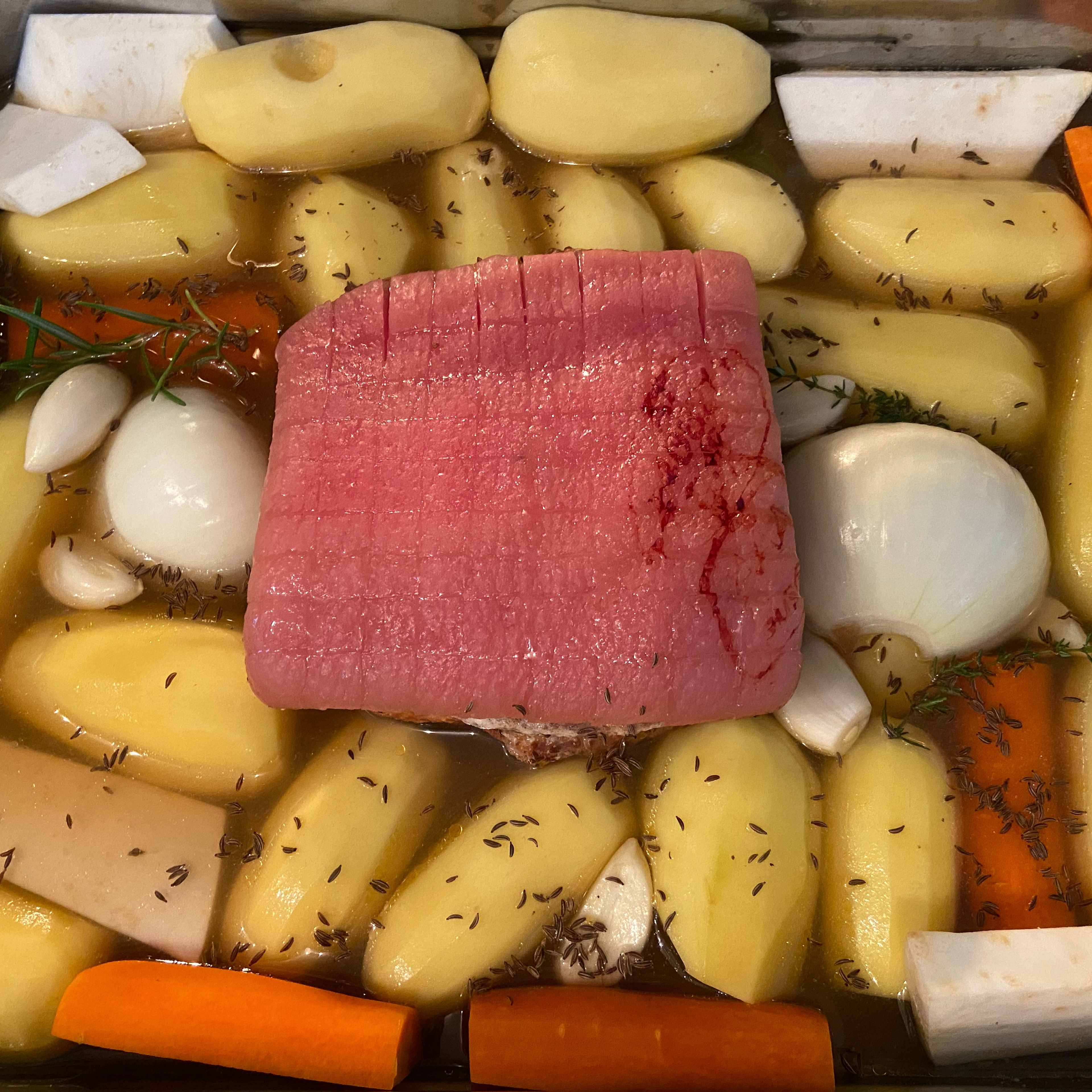 After approx. 30 min. turn the pork belly over and score the rind. Add the vegetables to the roasting pan, add water or stock. (the vegetables should not be completely covered) Add 1/2 tbsp caraway seeds, 2 bay leaves, 1 sprig of rosemary and thyme and transfer back to the oven for approx. 1 1/2–2 hrs. at 150°C/300°F.