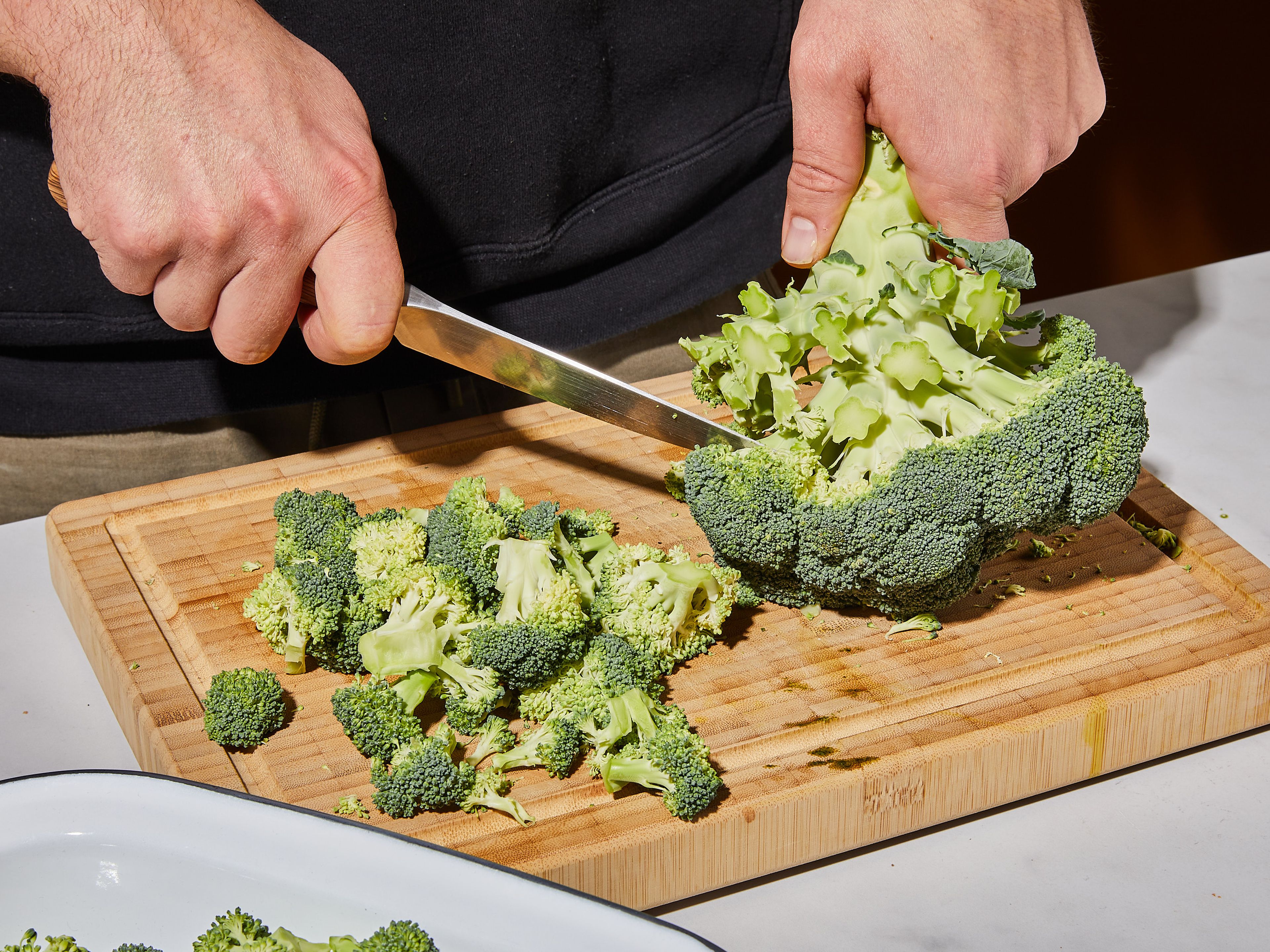 Den Backofen auf 190°C vorheizen. Den Brokkoli in mittelgroße Röschen schneiden. Anschließend die Zwiebeln und den Knoblauch würfeln.