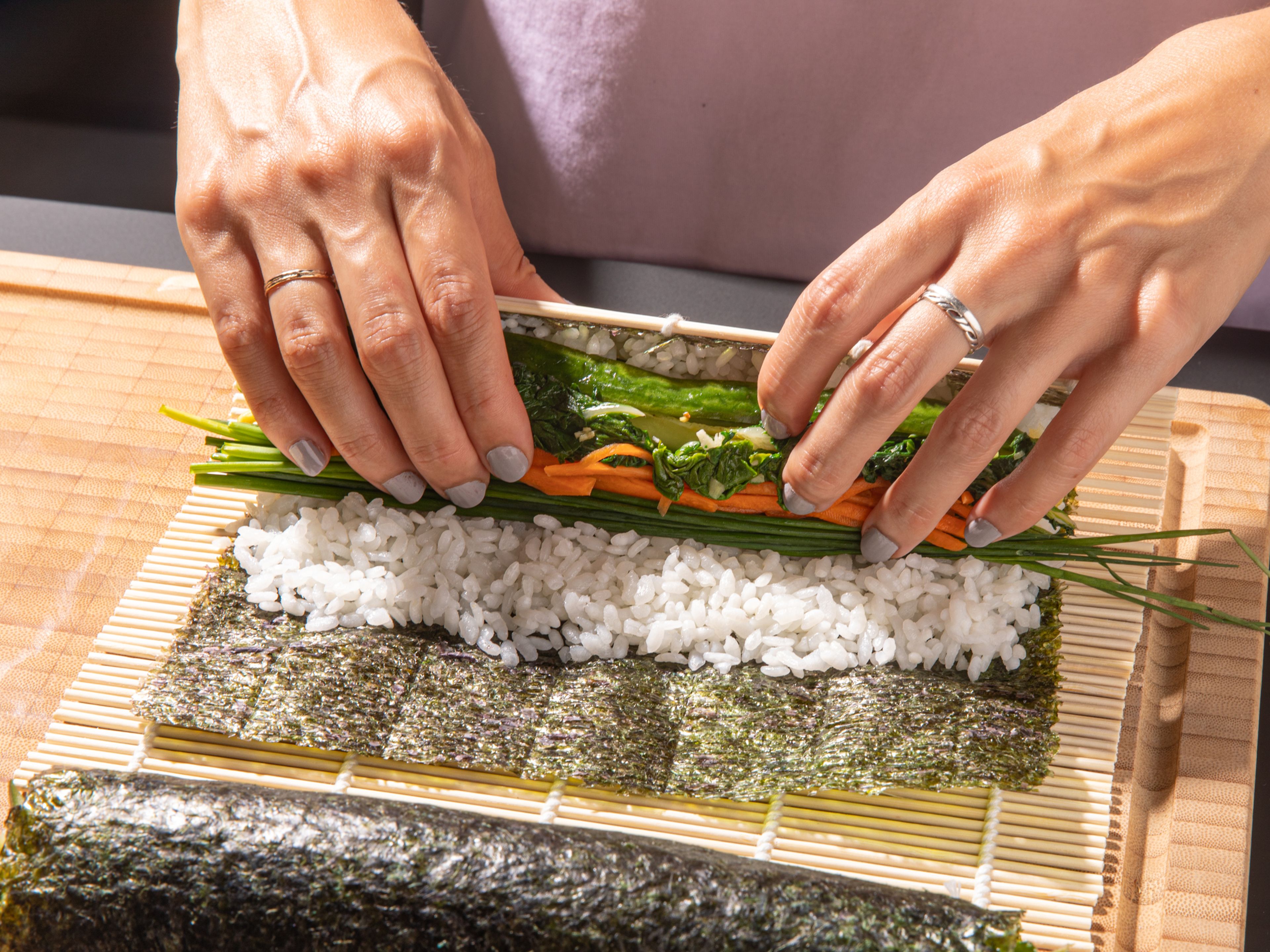 To assemble the kimbap, place a sheet of nori (shiny side down) on a bamboo rolling mat. Spread half the rice over the nori, leaving about 2 inches exposed on the top. Place half the green beans, Swiss chard, chives, egg strips, and pickled cucumber and carrot (draining well) into the center of the rice. Use the mat and both hands to help you roll the kimbap, pressing it into a very tight roll. Remove the roll and repeat. Brush the kimbap with some toasted sesame oil, then slice into thick pieces. Serve immediately or pack up and enjoy later!