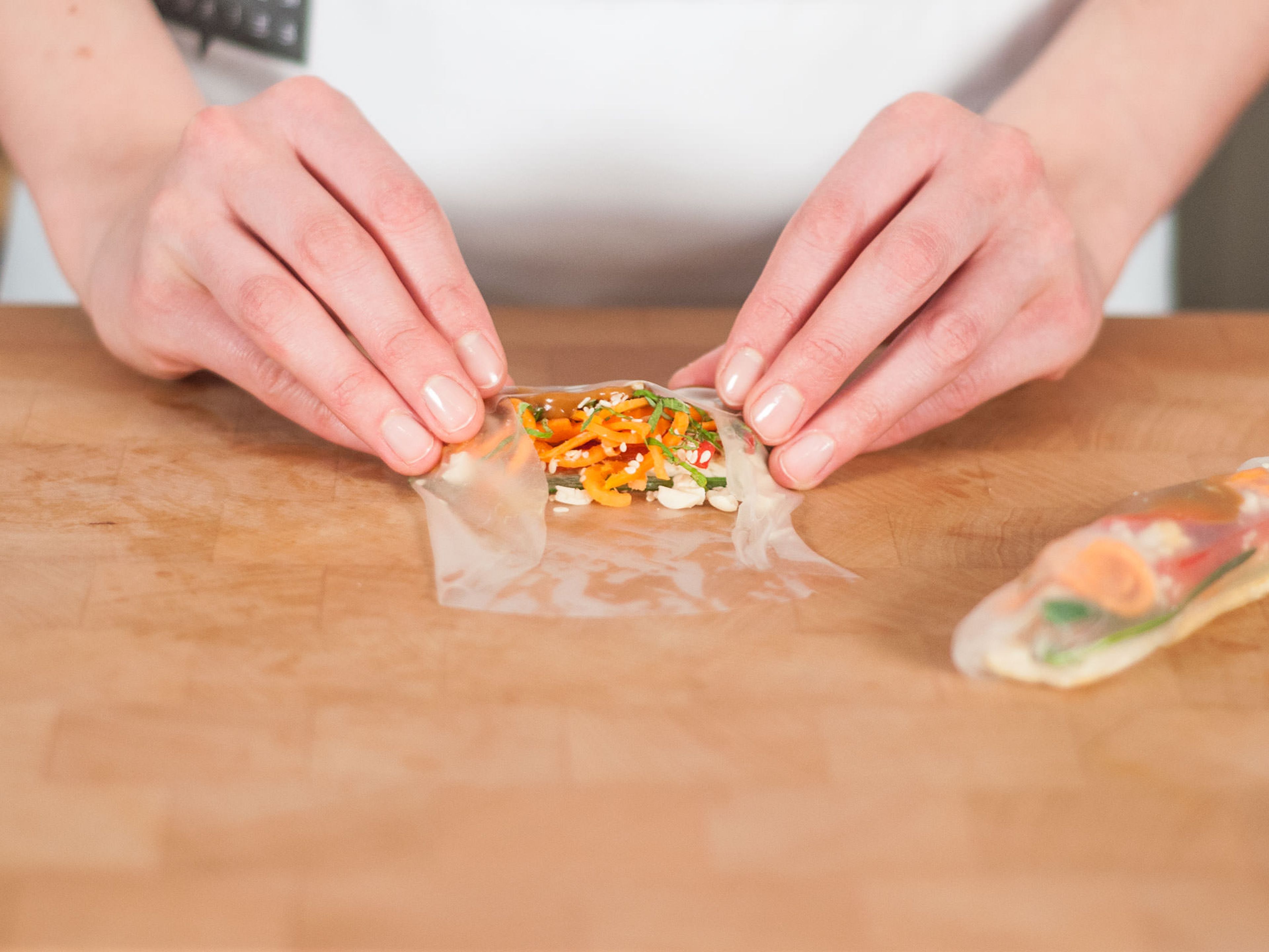 In the same way you wrap a tortilla, fold the edges of the rice wrapper towards the center, bring forward the bottom, and roll forward with your thumbs until the roll is tight. Garnish the roll with sesame seeds and serve with a dipping sauce of your choice. Enjoy!
