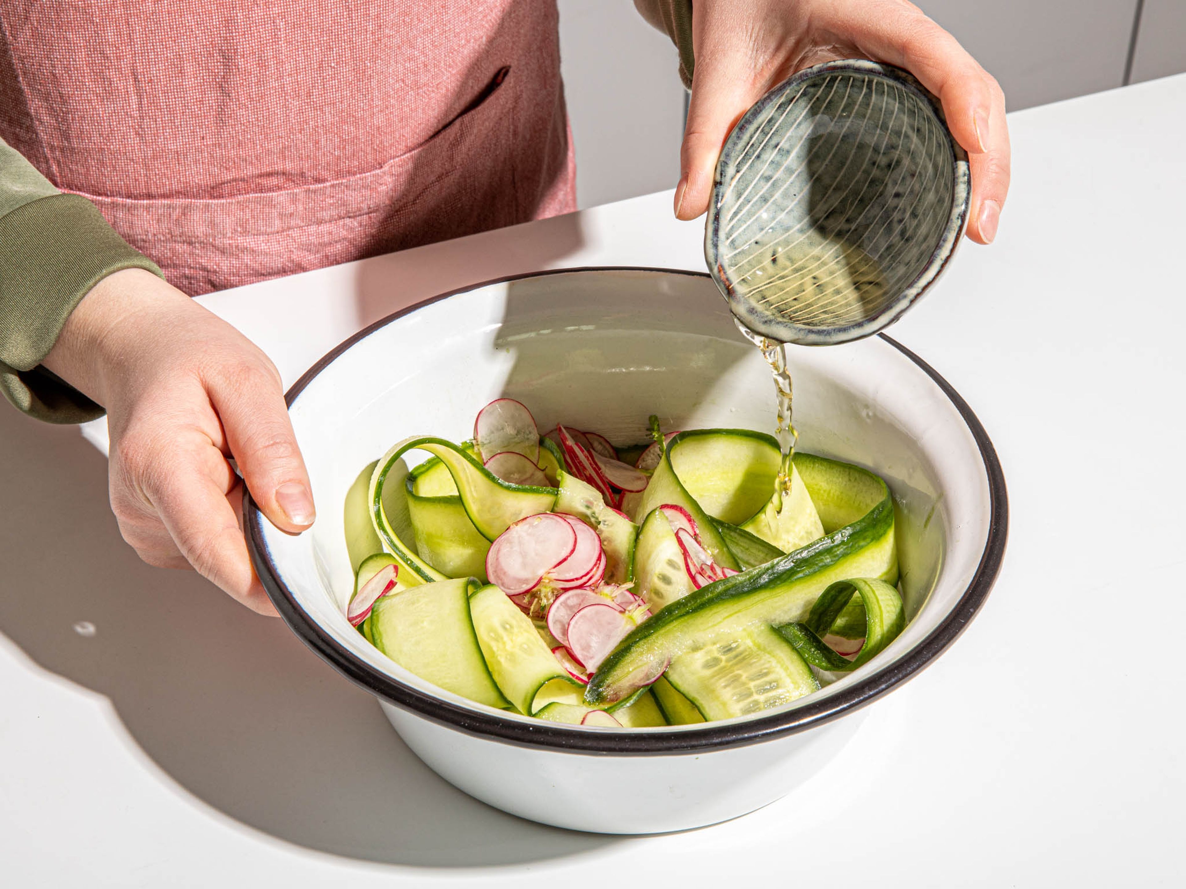 Thinly slice garlic, grate ginger, and set aside. Slice scallions on a diagonal and thinly slice cucumber and radishes. Add cucumber and radish to a medium bowl with rice wine vinegar. Season with salt and massage the vegetables with your hands to soften. Set aside to marinade.