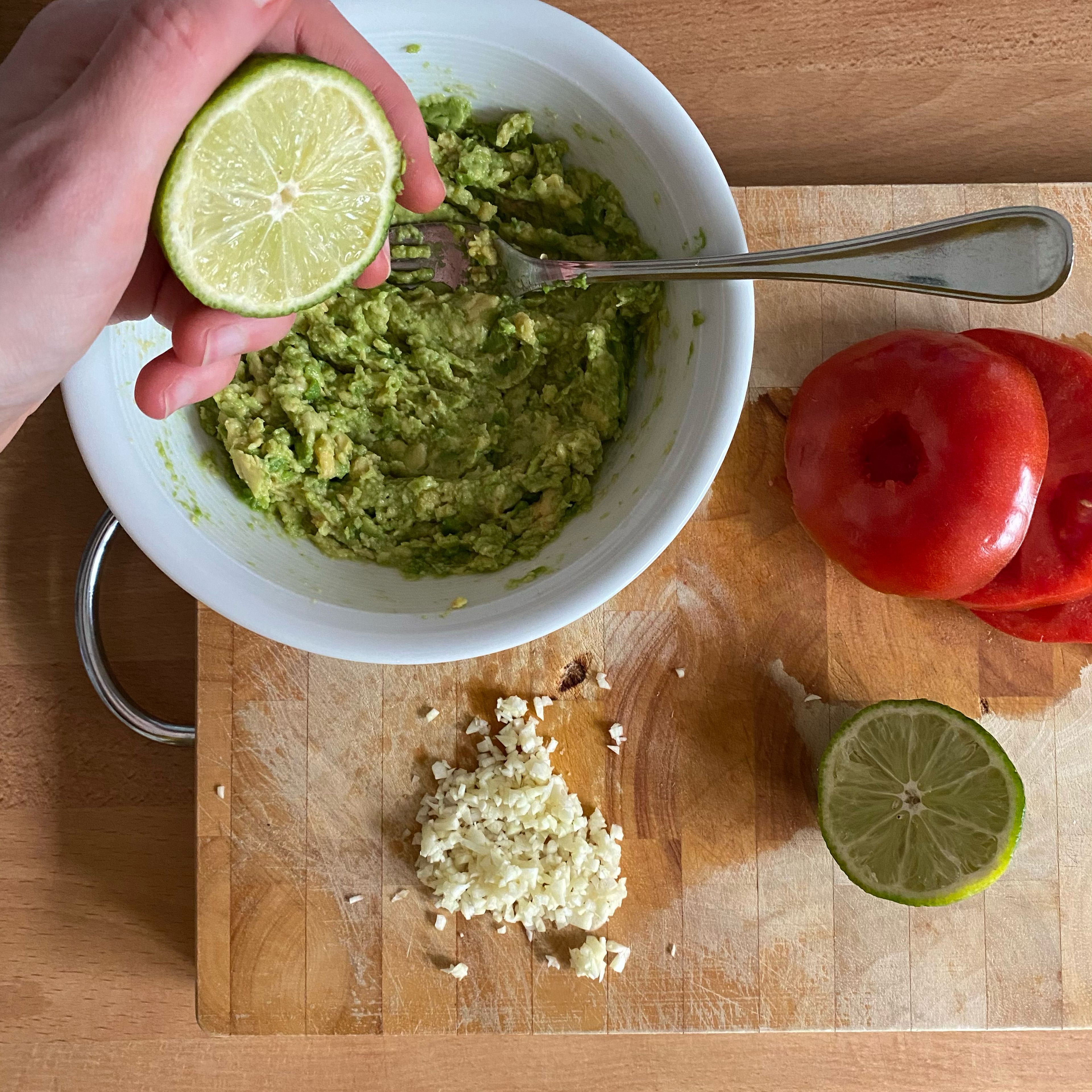 Die Burgermasse etwas durchziehen lassen. Den Strunk der Tomate entfernen und die Tomate quer in 6 Scheiben schneiden. Den Knoblauch schälen und fein hacken. Das Fruchtfleisch der Avocado mit einer Gabel zerdrücken.