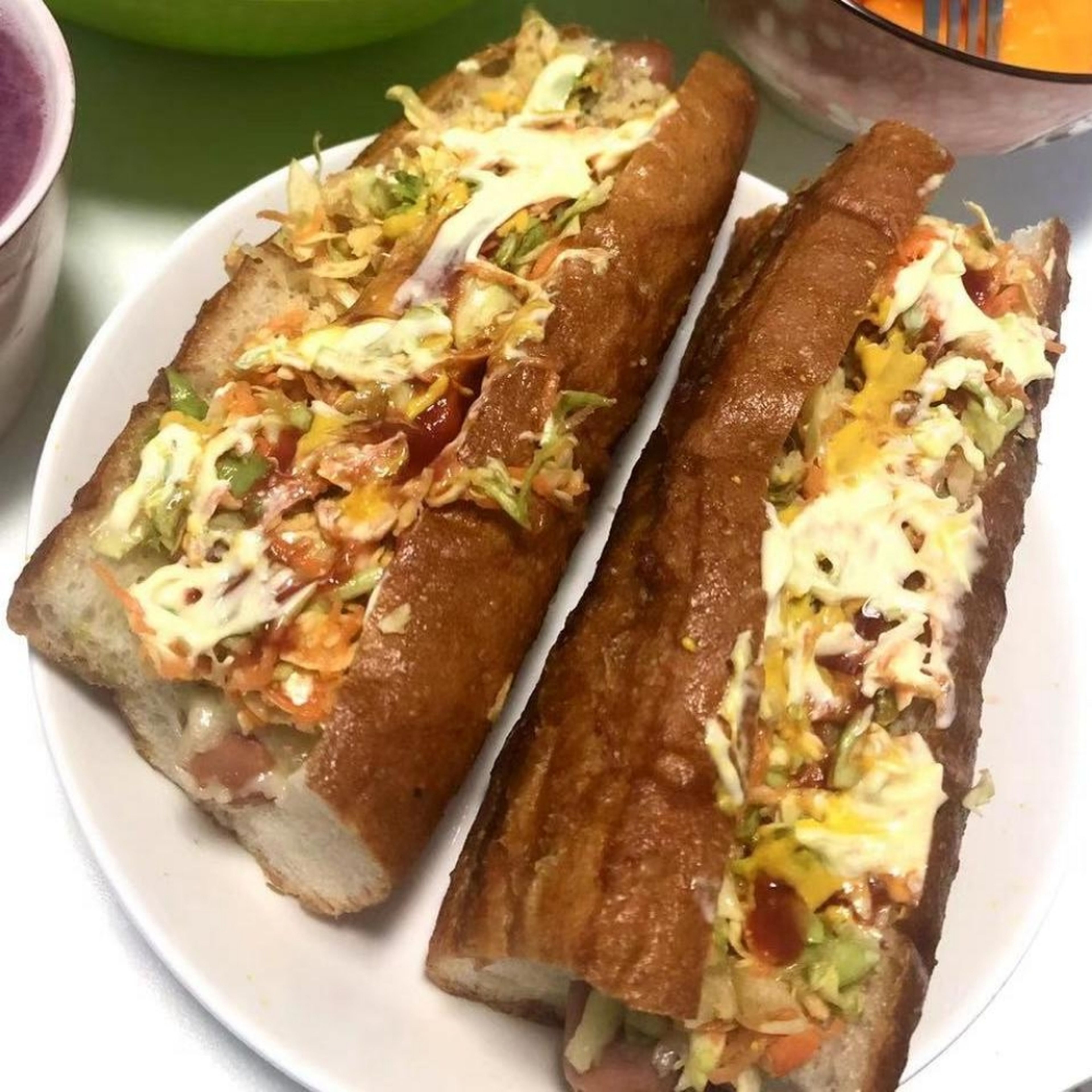Take out the bread from the microwave, on top of the melted cheese add a layer of crushed potato chips, subsequently add a layer of the salad and lastly finish by covering the hotdog with mayonnaise, ketchup and mustard. Serve immediately and enjoy with your favorite drink and favorite people.