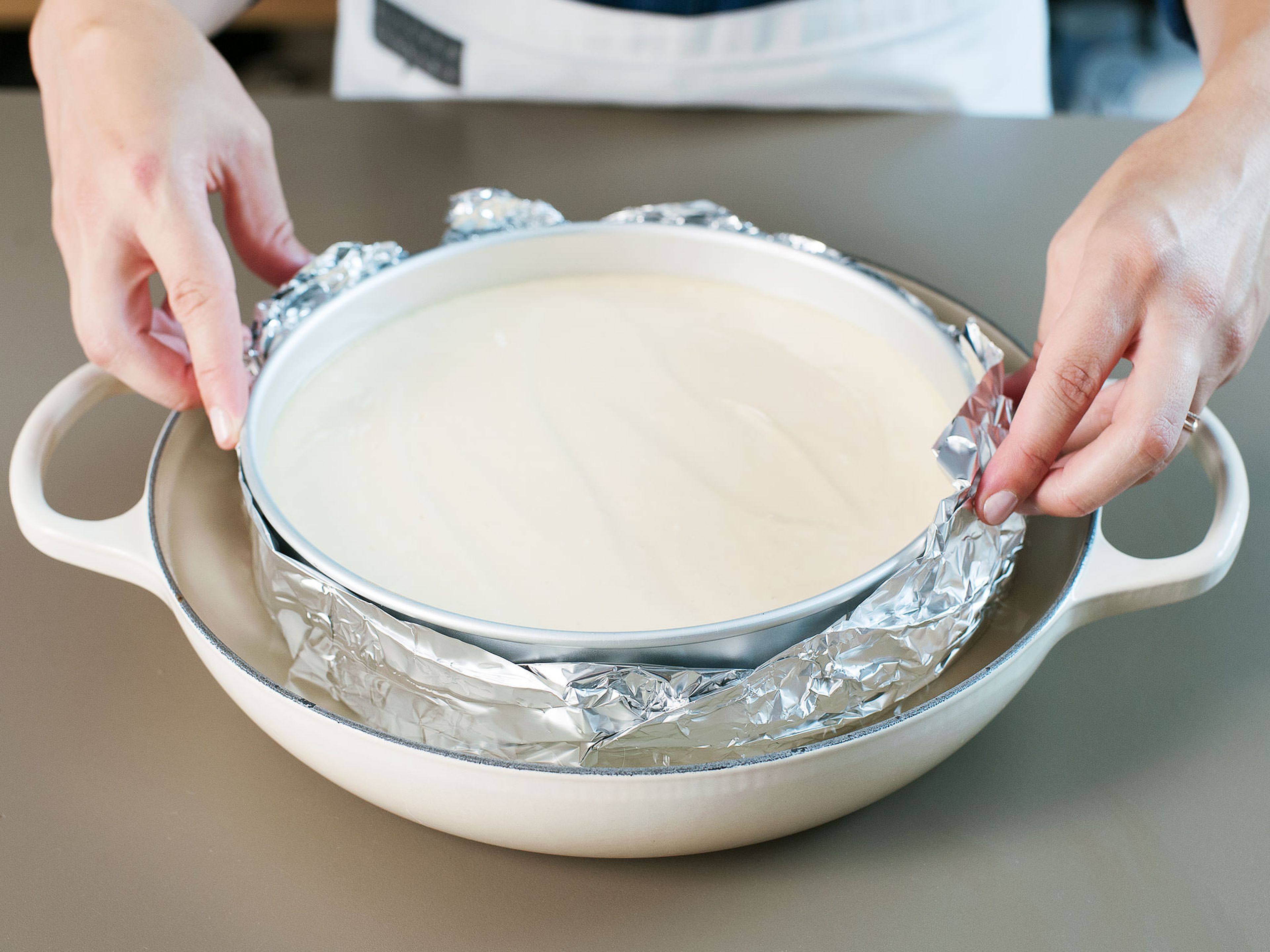 Place cake pan into a deep baking dish and fill with approx. 2 cm./1 in. of boiling water so that the bottom of the pan is submerged. Bake on lowest rack of oven at 160°C/320°F for approx. 50 min. Check on the cheesecake after 30 min. and cover with parchment paper if the top of the cake is getting too dark. When cake is done baking, remove the aluminum foil from the pan. Run a thin knife around the edge of cake to loosen it and prevent it from cracking as it cools. Leave to cool on a rack for approx. 2 hours. Transfer to refrigerator and chill for a minimum of 6 hours before serving.