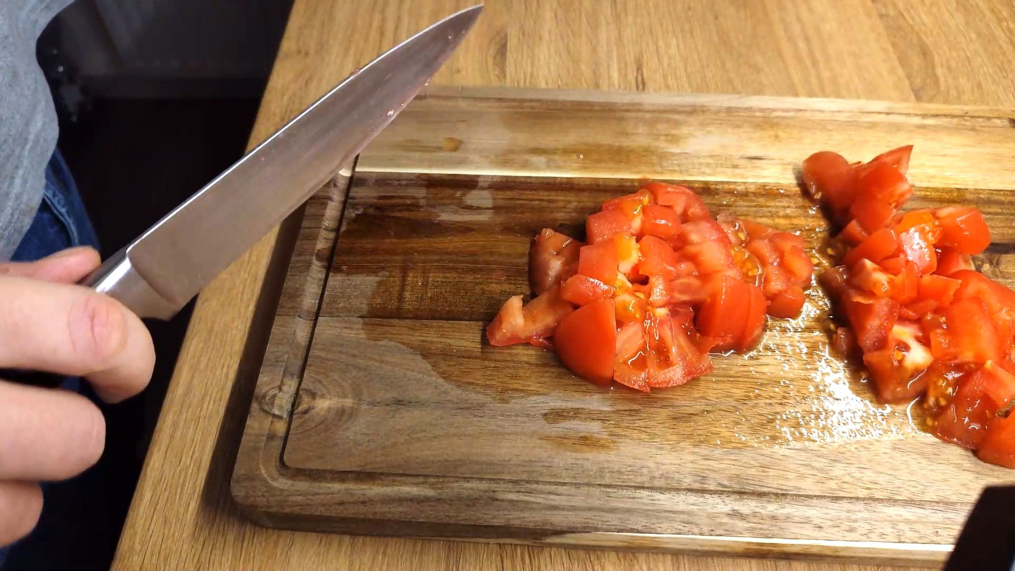 Inzwischen die Zwiebel klein schneiden. Die Tomate enthäuten und in bissfertige Stücke schneiden. 