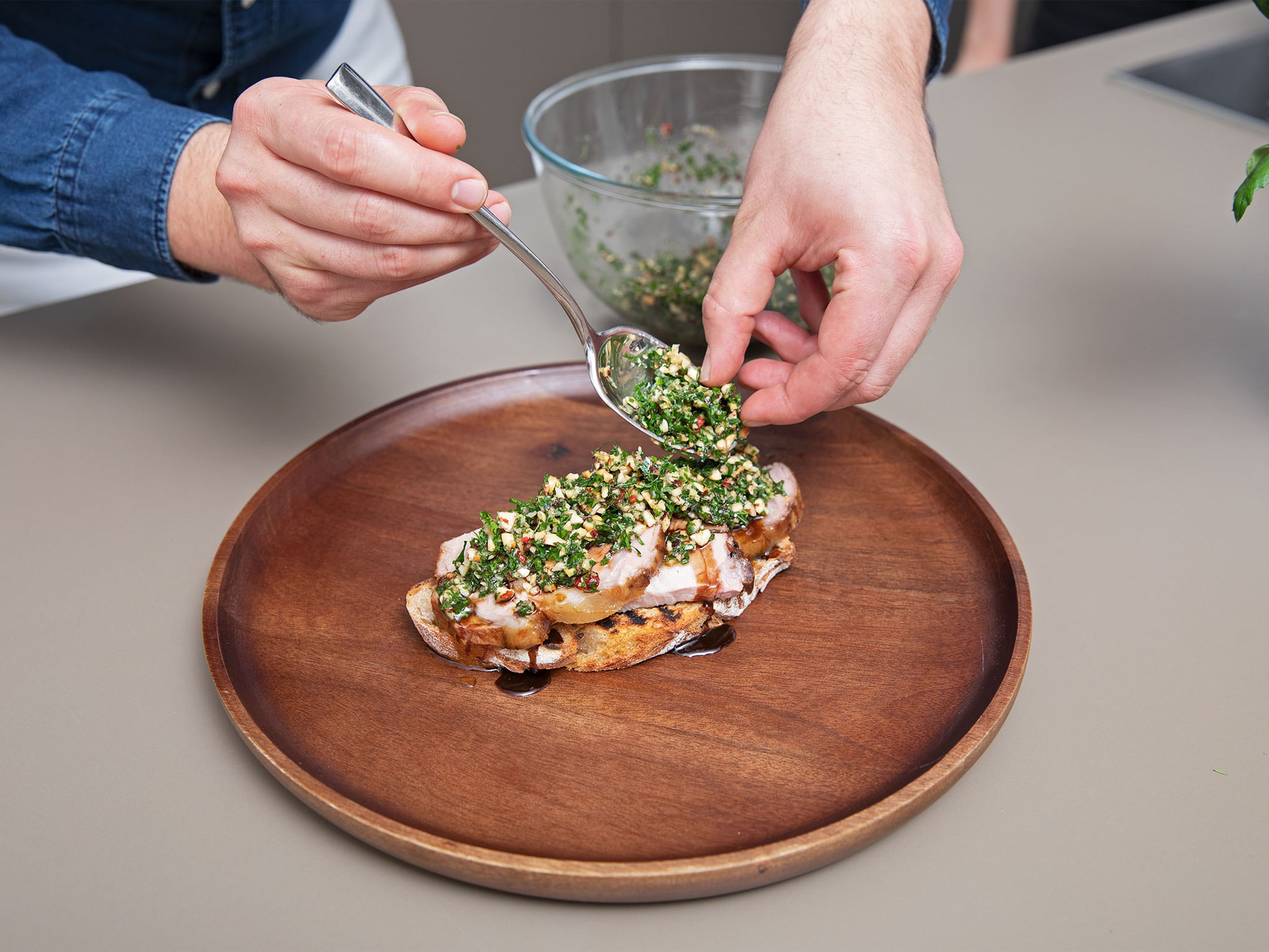To assemble the toasts, pile a portion of sliced pork on top of the toasted sourdough bread and drizzle with gravy. Finish with a spoonful of hazelnut gremolata. Enjoy!