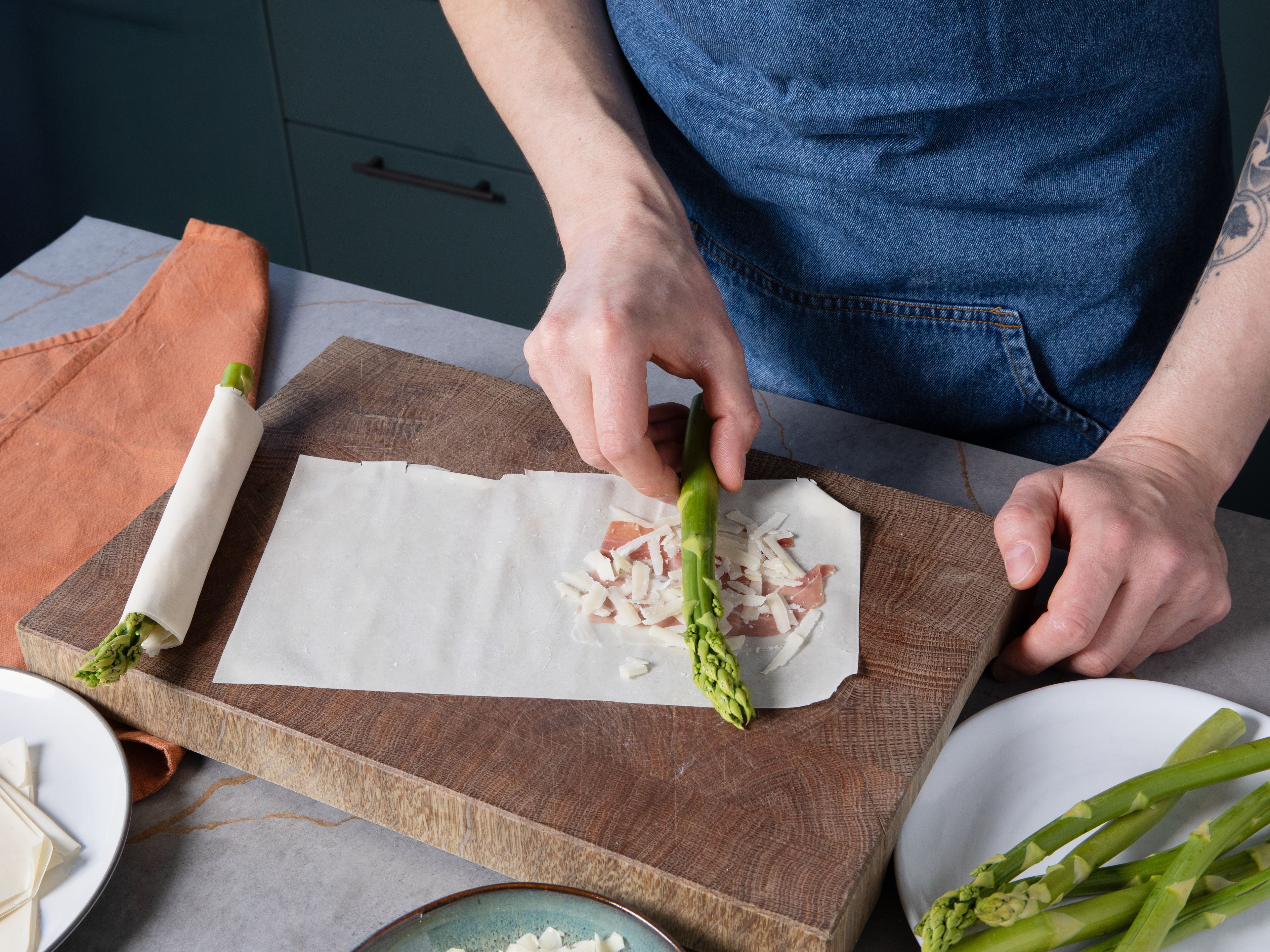 Place a piece of prosciutto on each filo rectangle, sprinkle with grated Parmesan, and lay an asparagus spear along the bottom edge. Season with salt and pepper, then roll the asparagus tightly in the pastry.