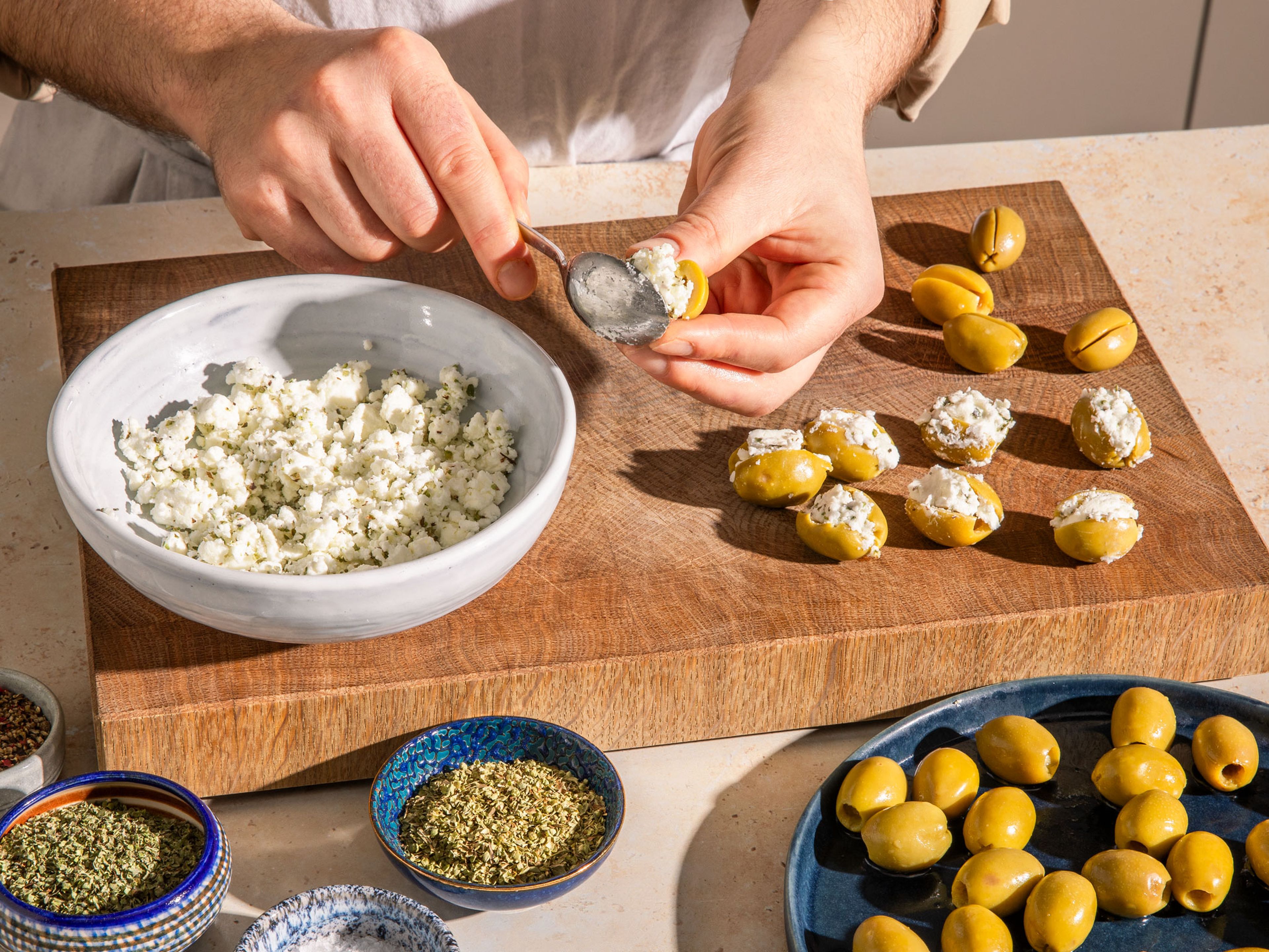 Fill ¾ of a medium-sized pot with frying oil. Place in a food thermometer and heat the oil to 356°F/180°C. If you don't have a thermometer, lower an olive carefully into the oil. The oil is ready if it sizzles slightly. While the oil is heating up, mash up feta with salt, pepper and dried mint and oregano. Slice olives open and stuff each olive generously with the feta mixture.