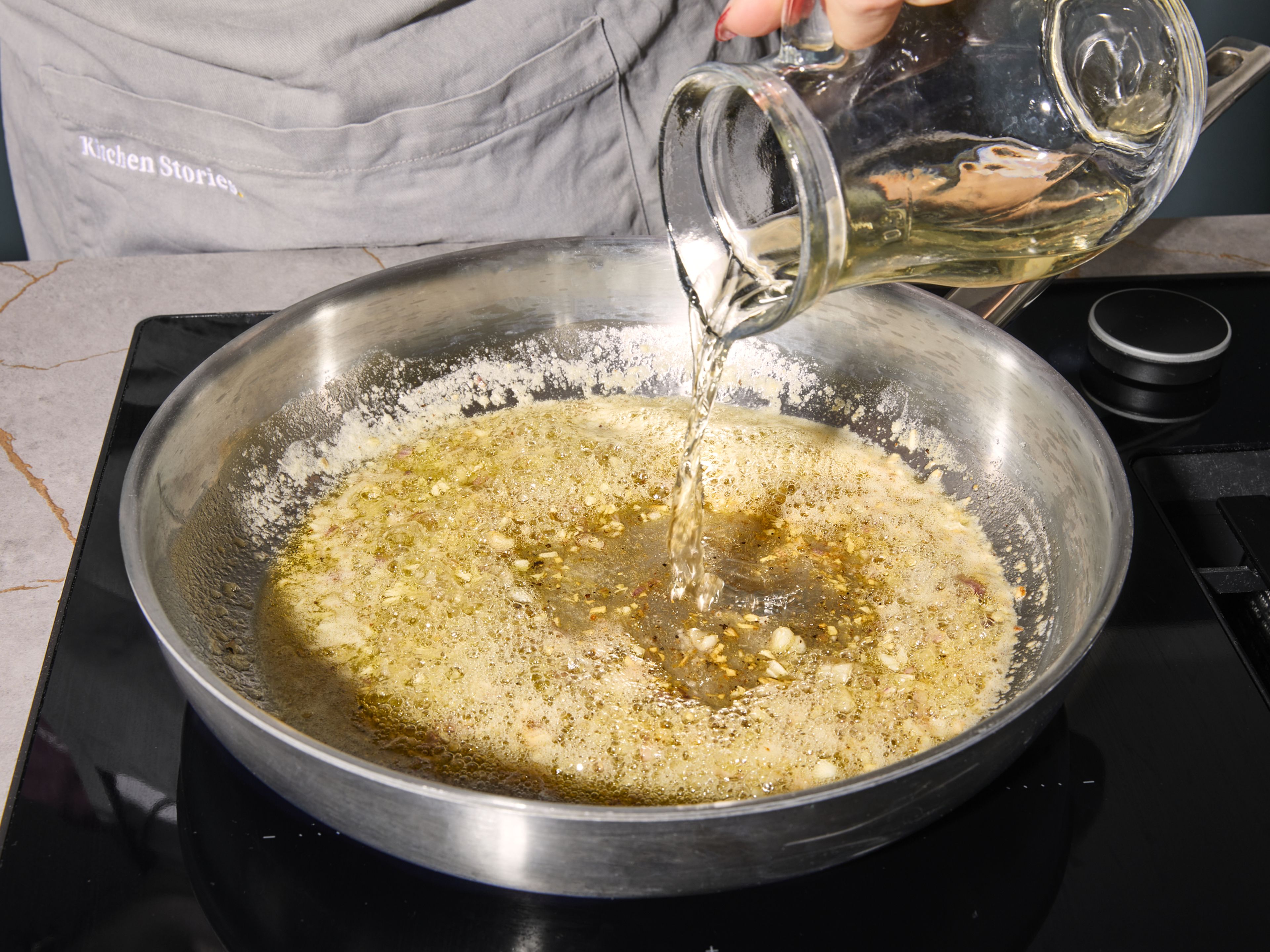Den Backofen auf 180°C Umluft oder 200°C Ober-Unterhitze vorheizen. Dafür sorgen, dass die Fischfilets aufgetaut sind und Zimmertemperatur haben. Zitrone abreiben und entsaften, Knoblauch und Schalotte fein hacken. Das
Ei in einer kleinen Schüssel verquirlen. In einer Bratpfanne bei mittlerer Hitze ⅔ der Butter schmelzen. Knoblauch und Schalotten zugeben und ca. 3 Min. lang glasig dünsten. Mit Weißwein und ⅓ des Zitronensafts ablöschen, mit Salz und Pfeffer würzen. Weitere ca. 4 Min. kochen.
